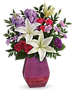 Regal Blossoms - Regale her with this royalty-worthy gift of roses and lilies! Mom will love the lush, fragrant blooms and stunning, hand-glazed ceramic art piece with glossy gradient finish.  This bouquet includes hot pink spray roses, white asiatic lilies, purple carnations, lavender stock, huckleberry, and lemon leaf.  Delivered in a Regal Blossoms vase.  Approximately 15 3/4" W x 20 1/2" H 