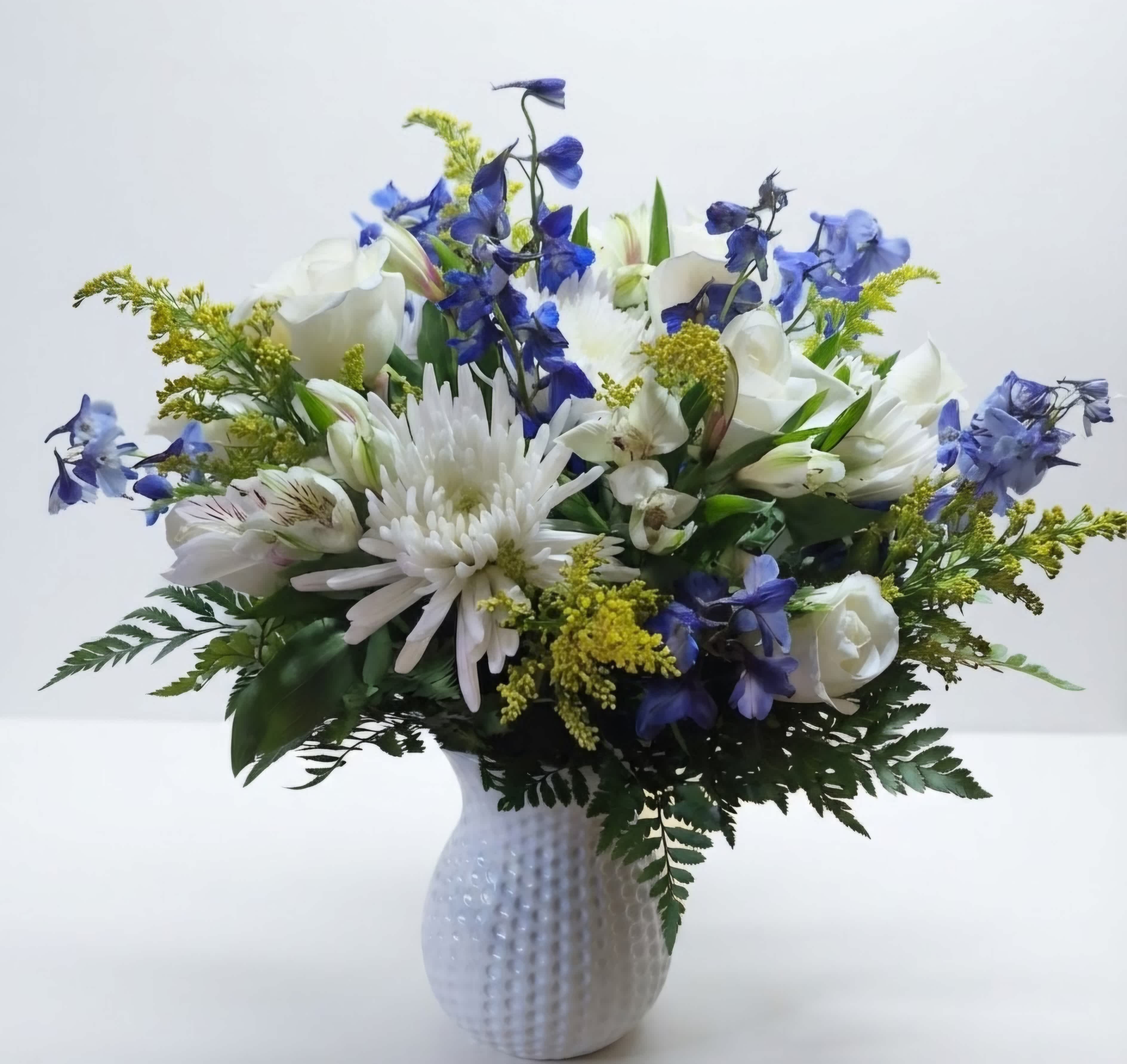 White and blue mixed flower arrangement in a textured white vase