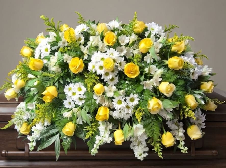 Yellow roses and white daisies arranged on a casket