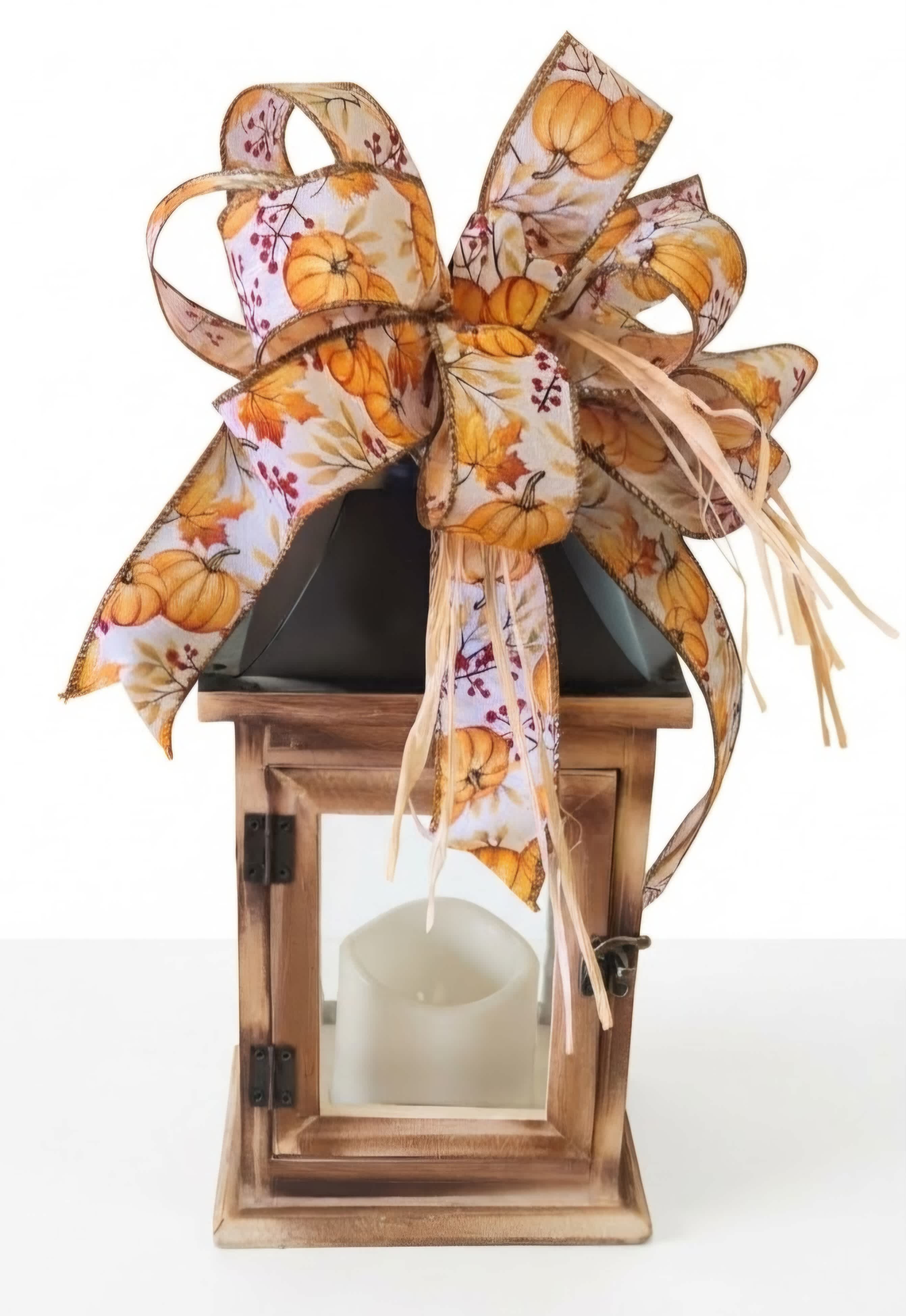 Decorative wooden lantern with a pumpkin-print ribbon bow and candle inside
