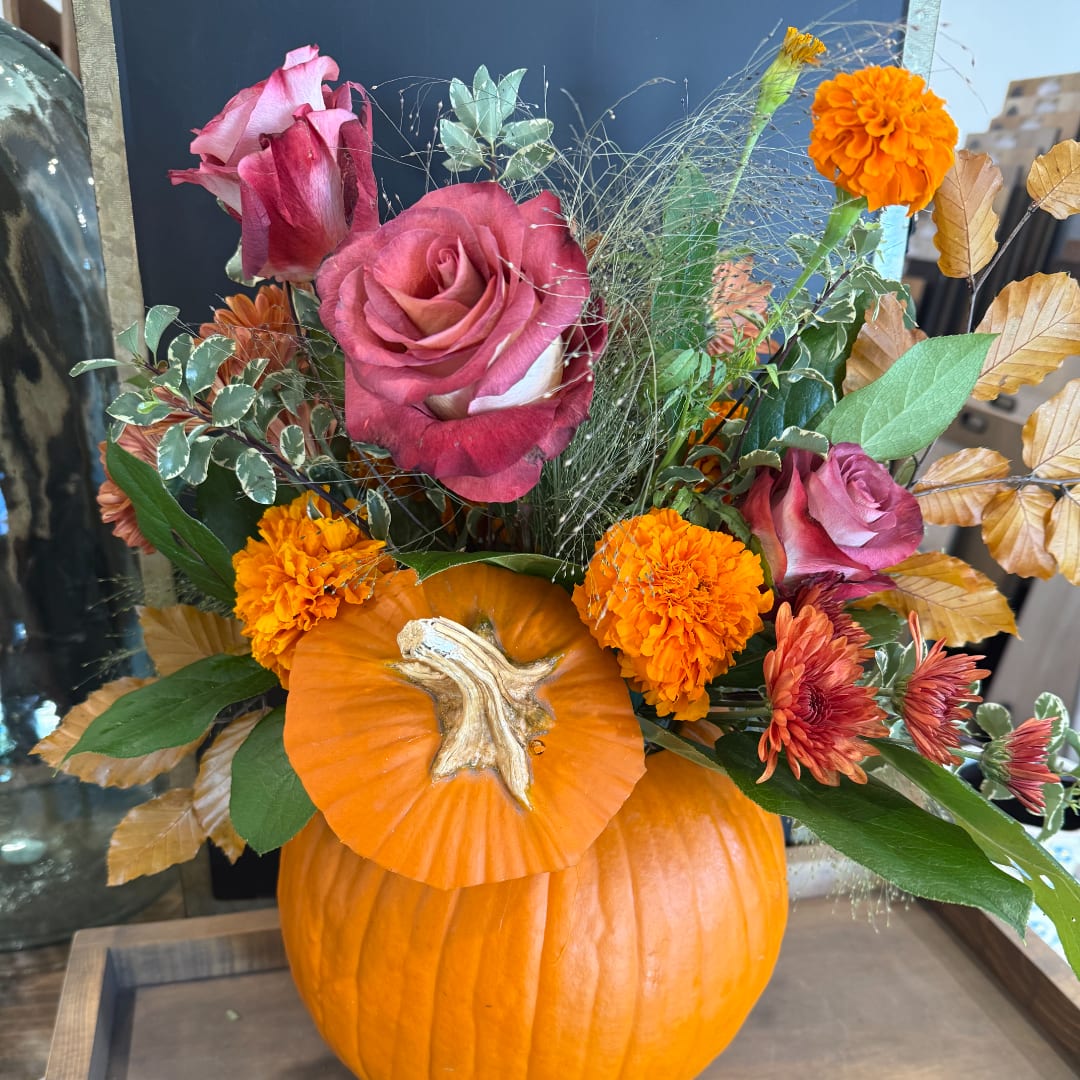 Pink roses and orange marigolds arranged in a pumpkin vase