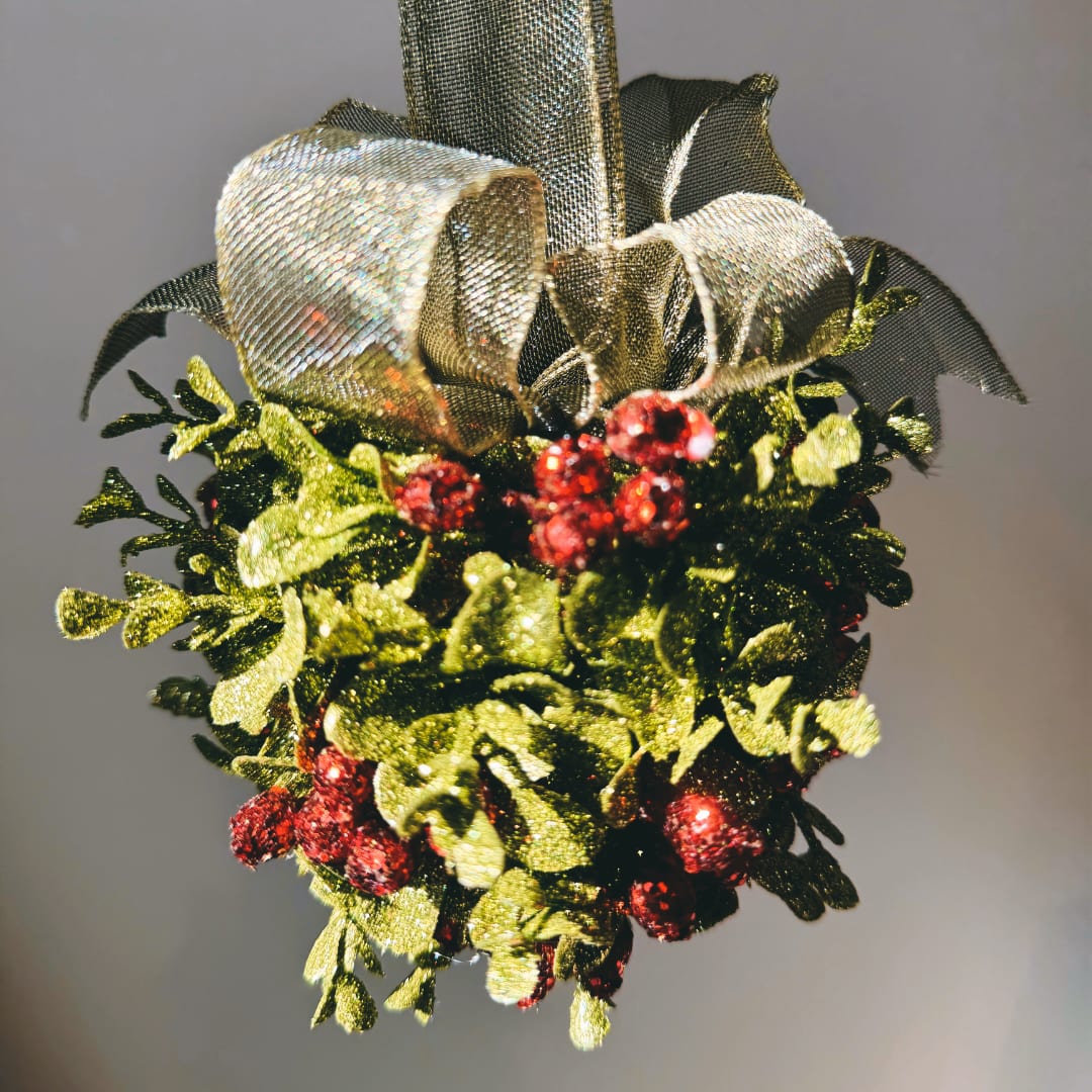 Decorative holiday greenery with red berries and a metallic bow