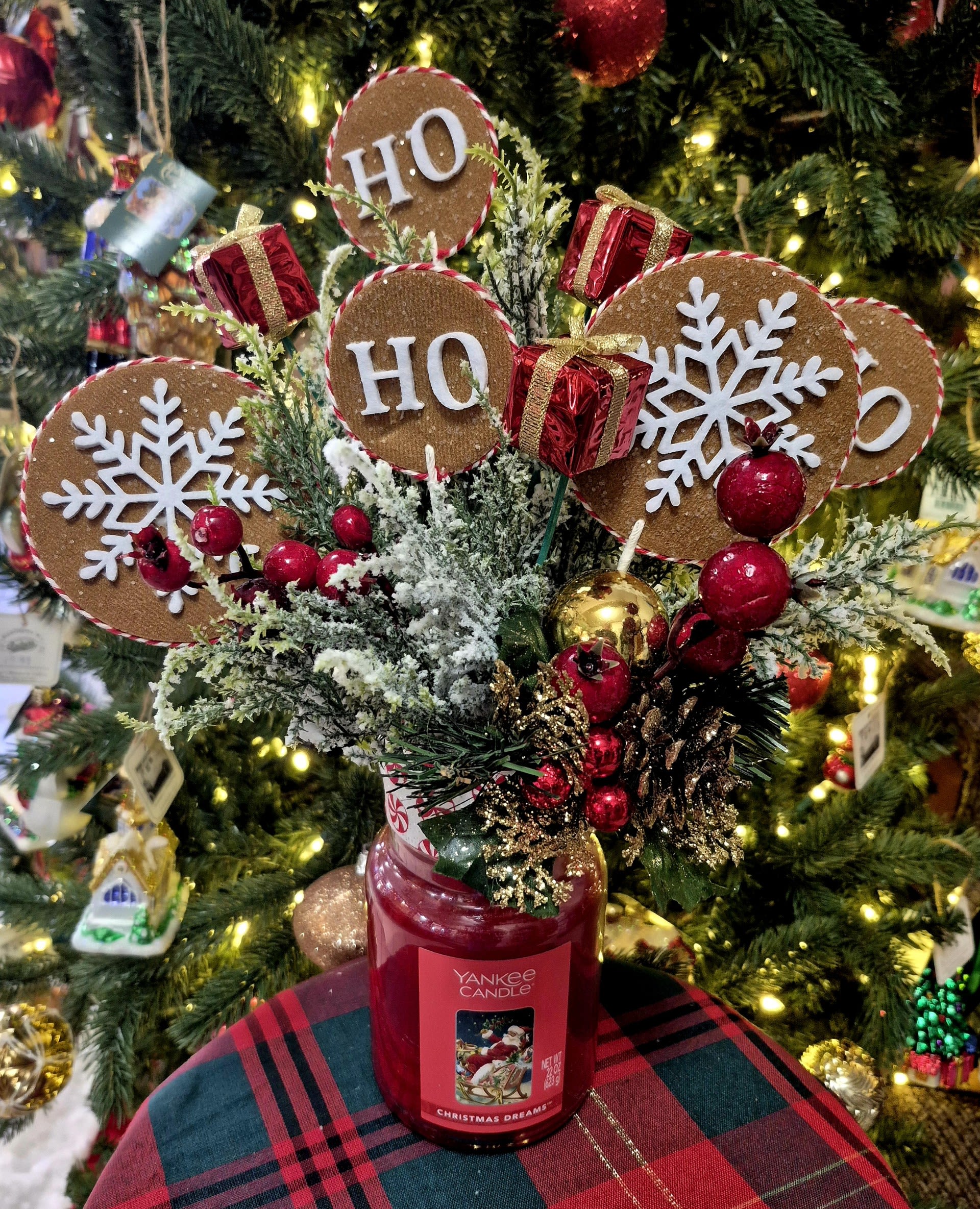 Christmas arrangement in a red candle jar with HO HO HO signs and ornaments