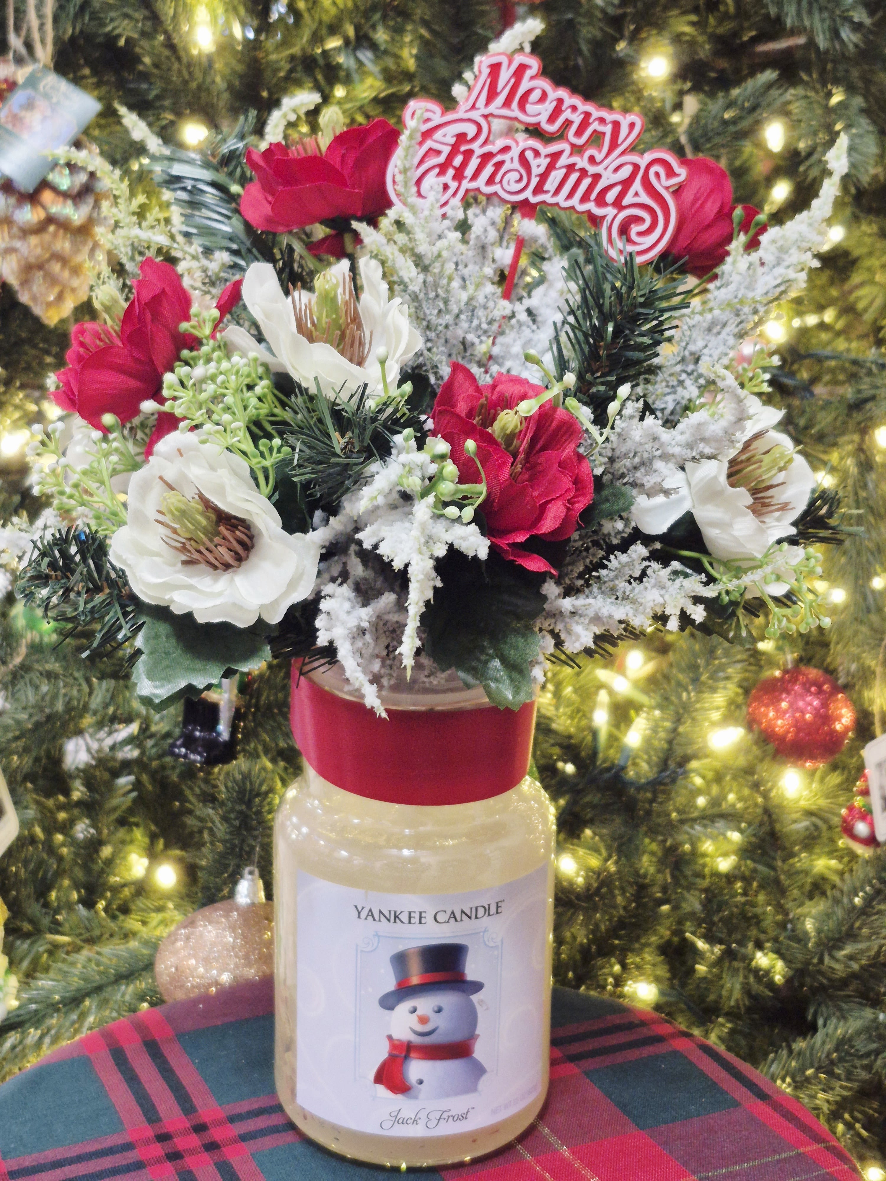 Holiday floral arrangement in a Yankee Candle jar with a Merry Christmas topper