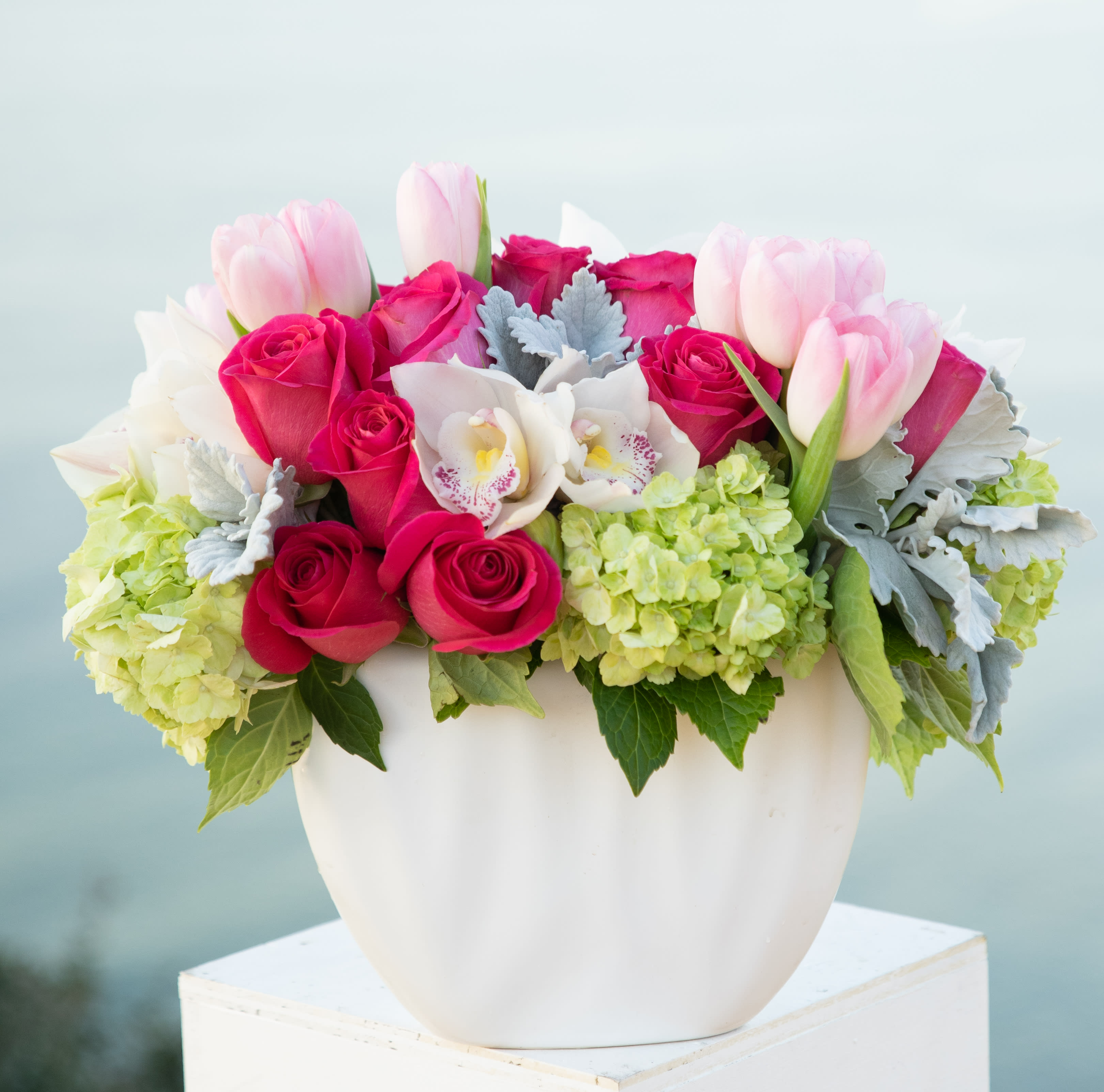 Pink roses and tulips arranged in a white vase