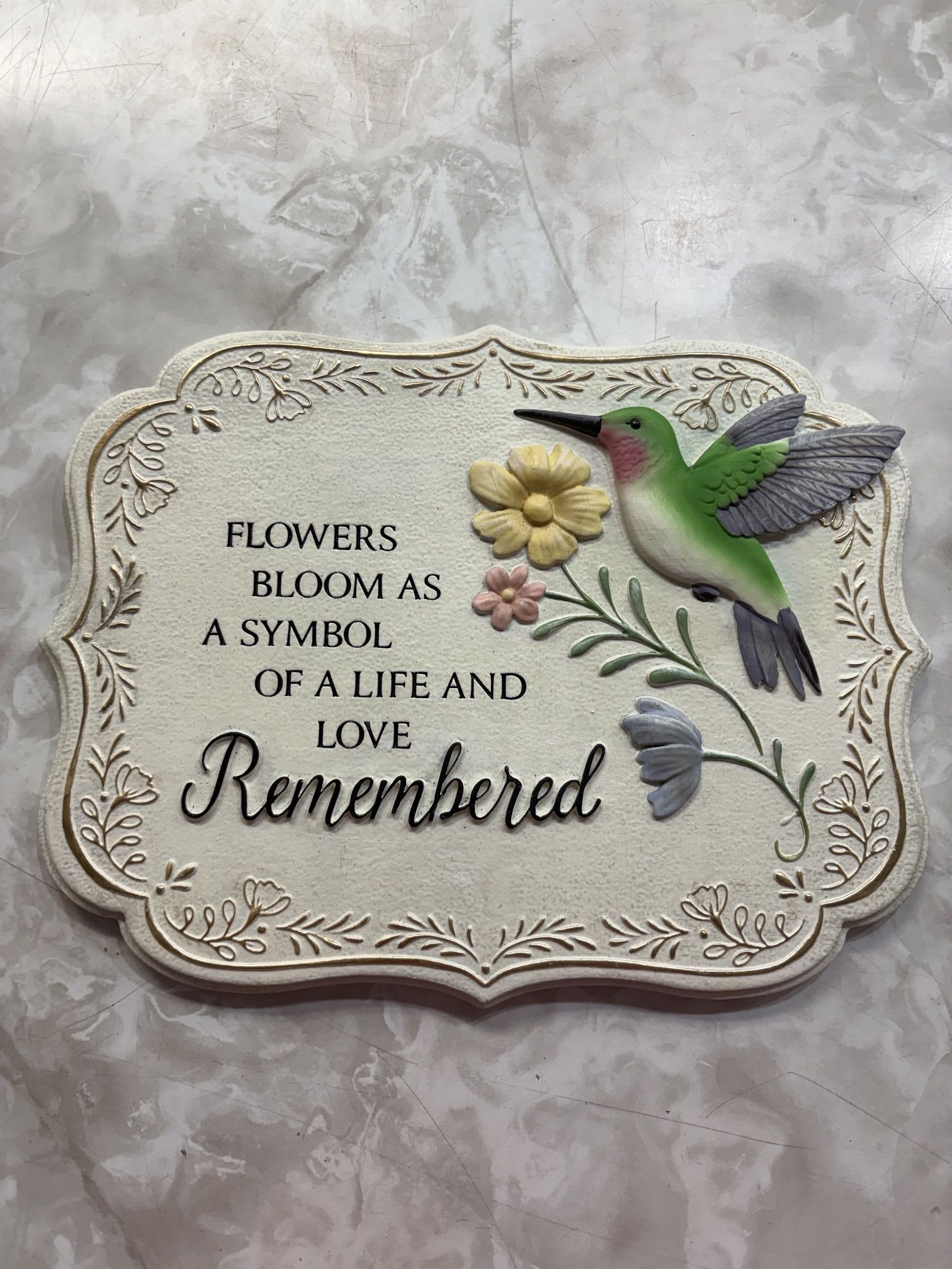 "Flowers Bloom" Hummingbird Garden Stone - This garden stone shows a Hummingbird and florals with a commemorating phrase: "Flowers Bloom as a Symbol of Life and Love Remembered."  10.5" x 8"