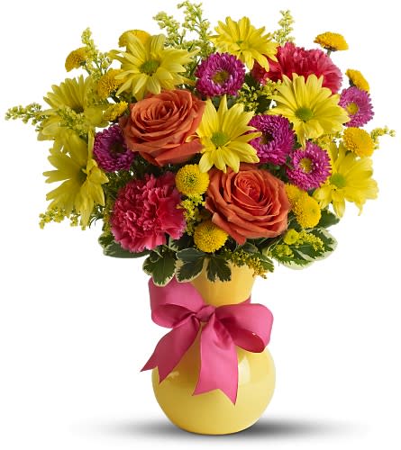 Colorful bouquet of roses, daisies, and carnations in a yellow vase with a pink ribbon