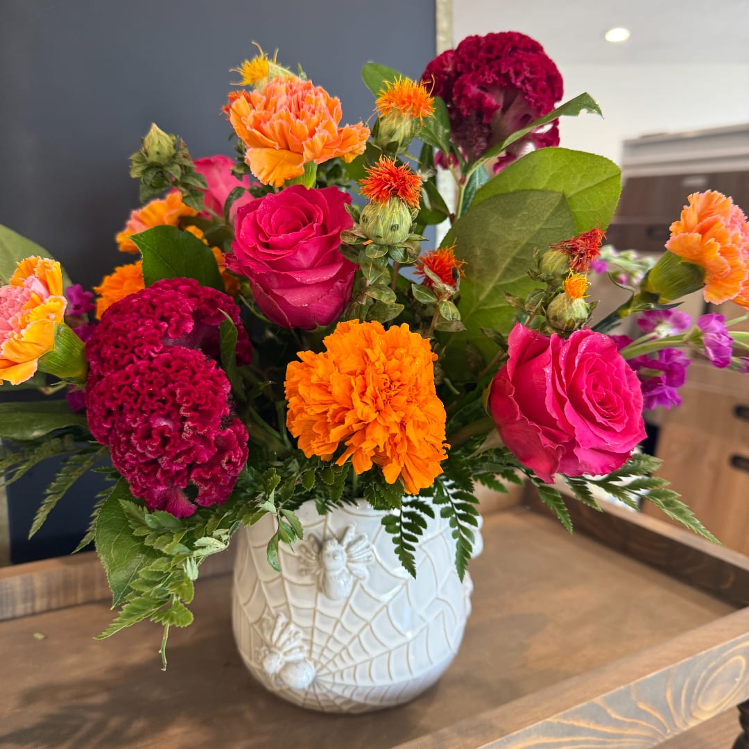 Bright mixed bouquet in a white ceramic vase with pink roses and orange carnations