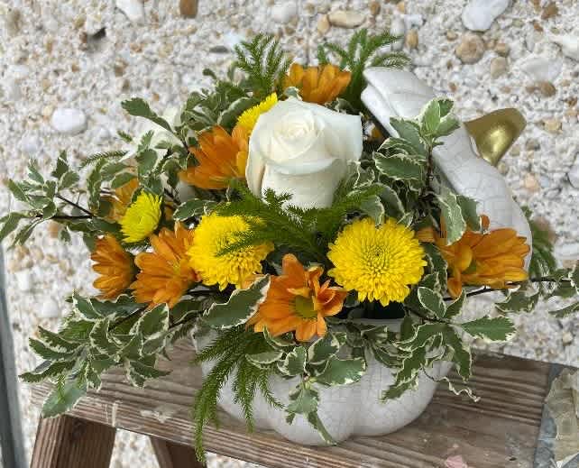 White rose and yellow-orange flowers in a white pumpkin container