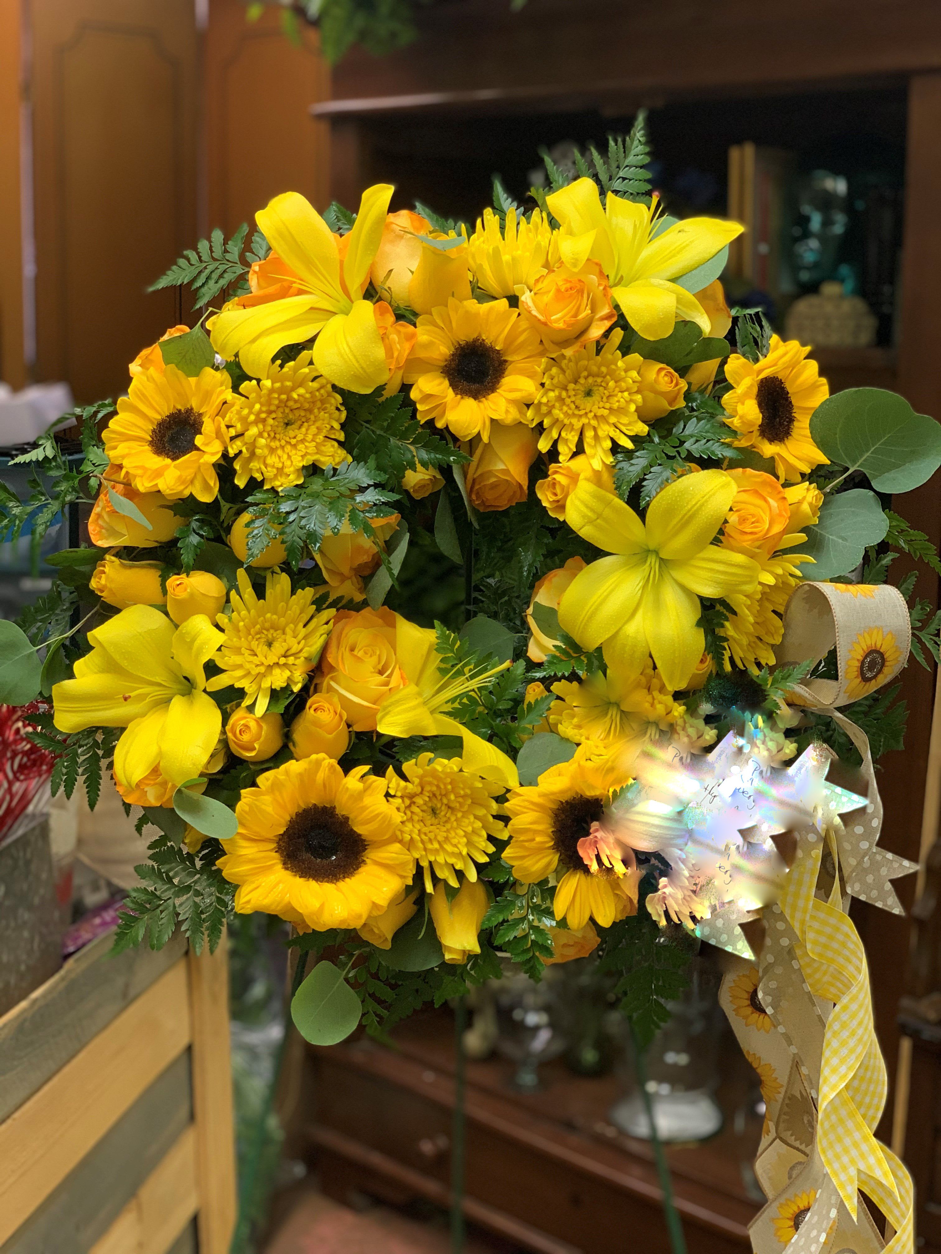 Sunny Daze - This beautiful all yellow memorial wreath wiill warm the hearts of everyone at the funeral or memorial. It's stunning aray of lilies, roses, sunflowers, and other bright and warm tone flowers.