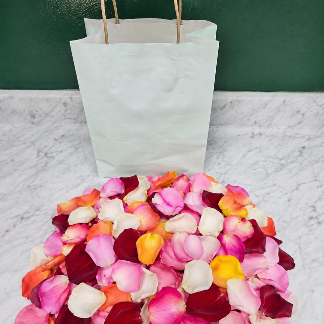 Pile of multicolored rose petals in front of white paper bags