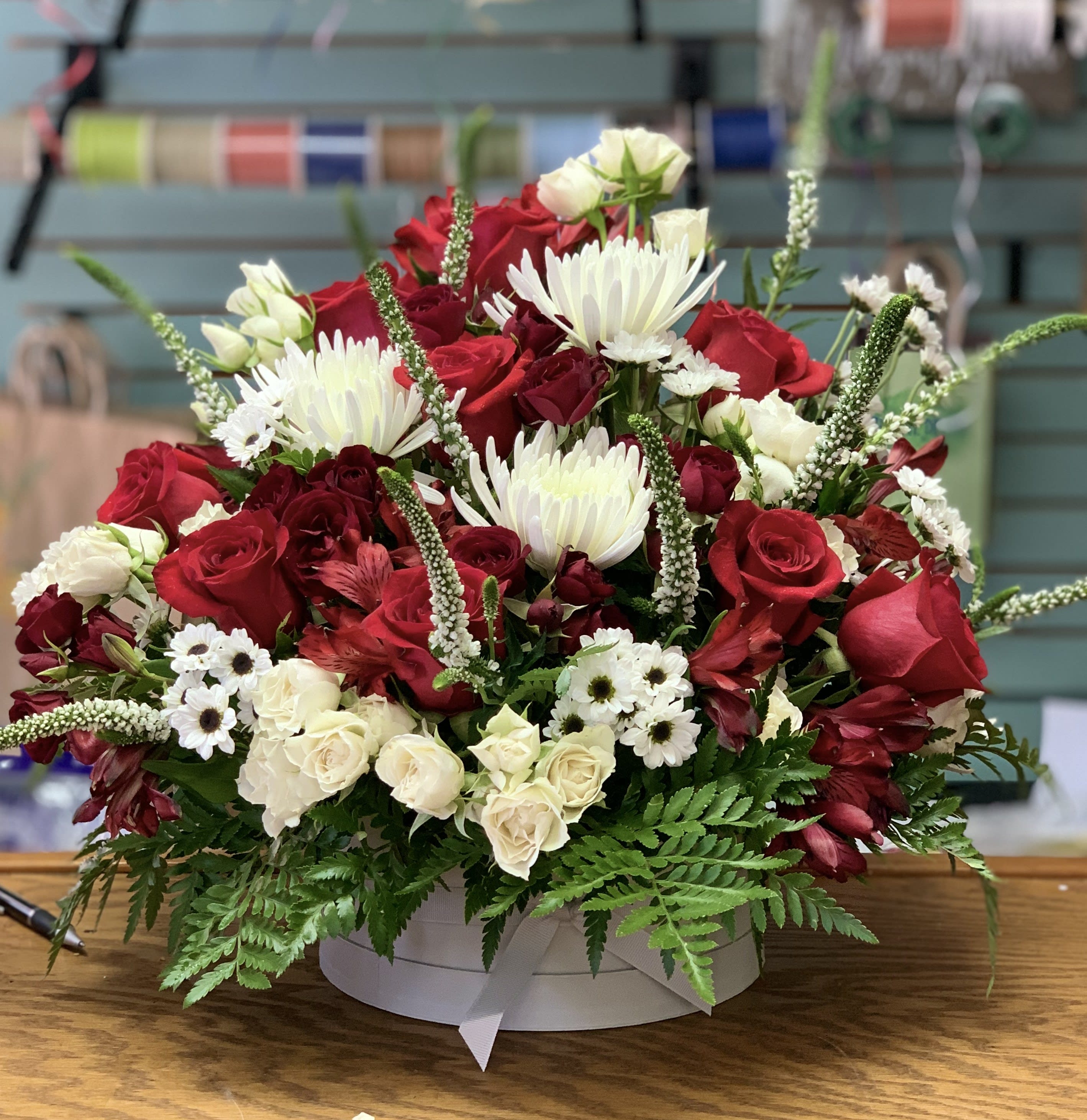 Red and white mixed flower arrangement in a round box