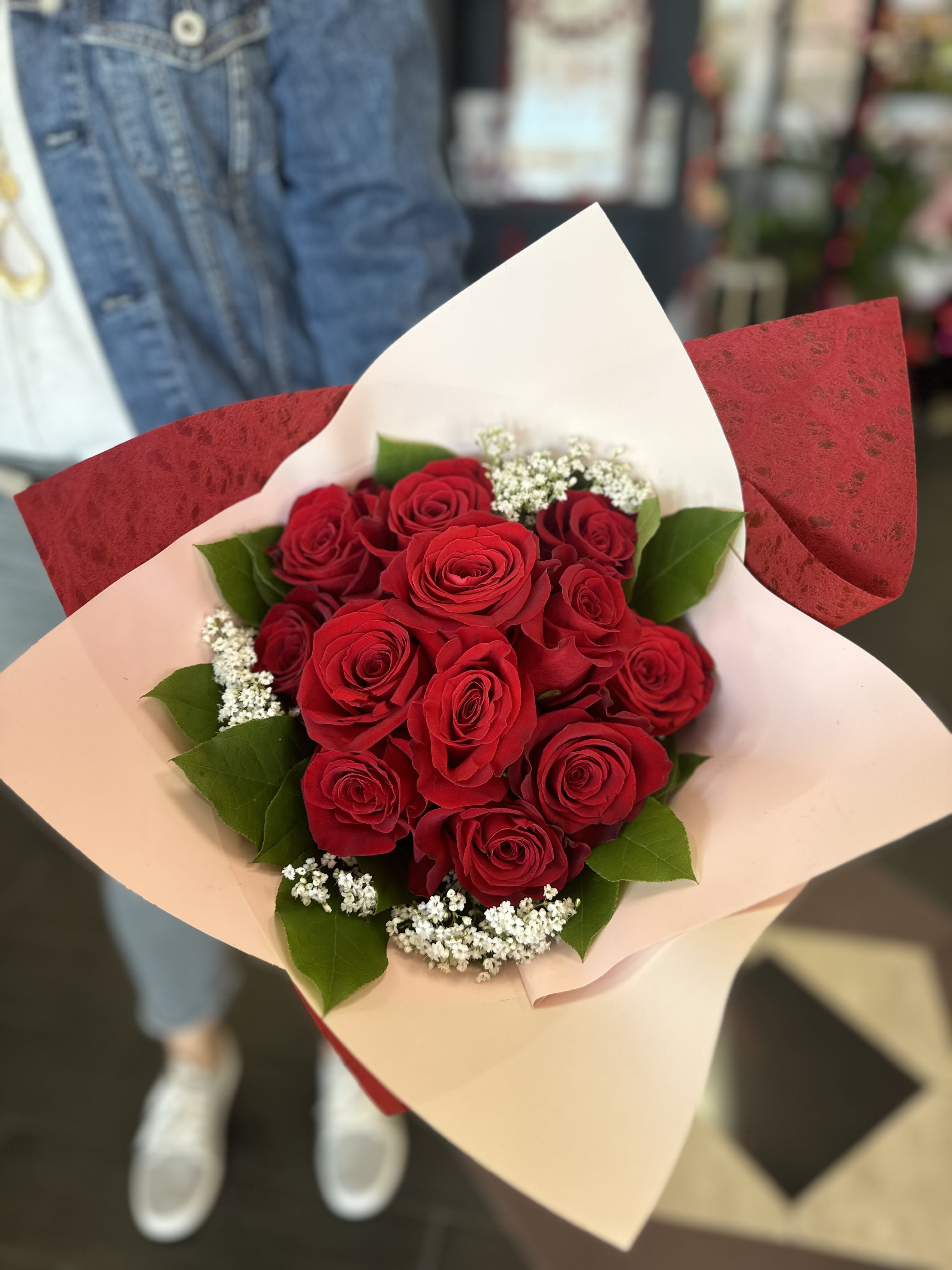 Bouquet of red roses with white filler flowers in pink and red wrap