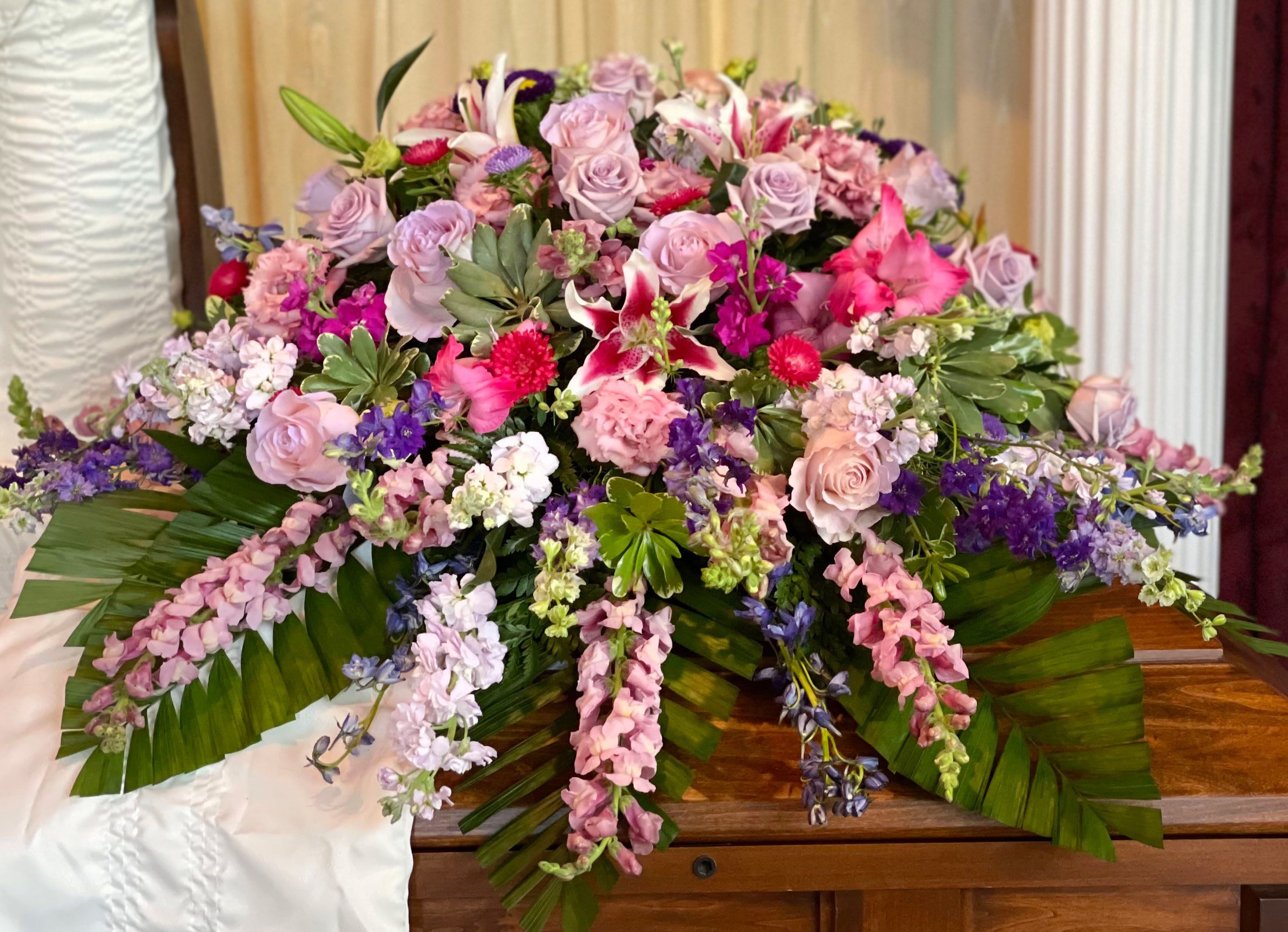 Large pink and lavender floral casket spray with lilies and roses