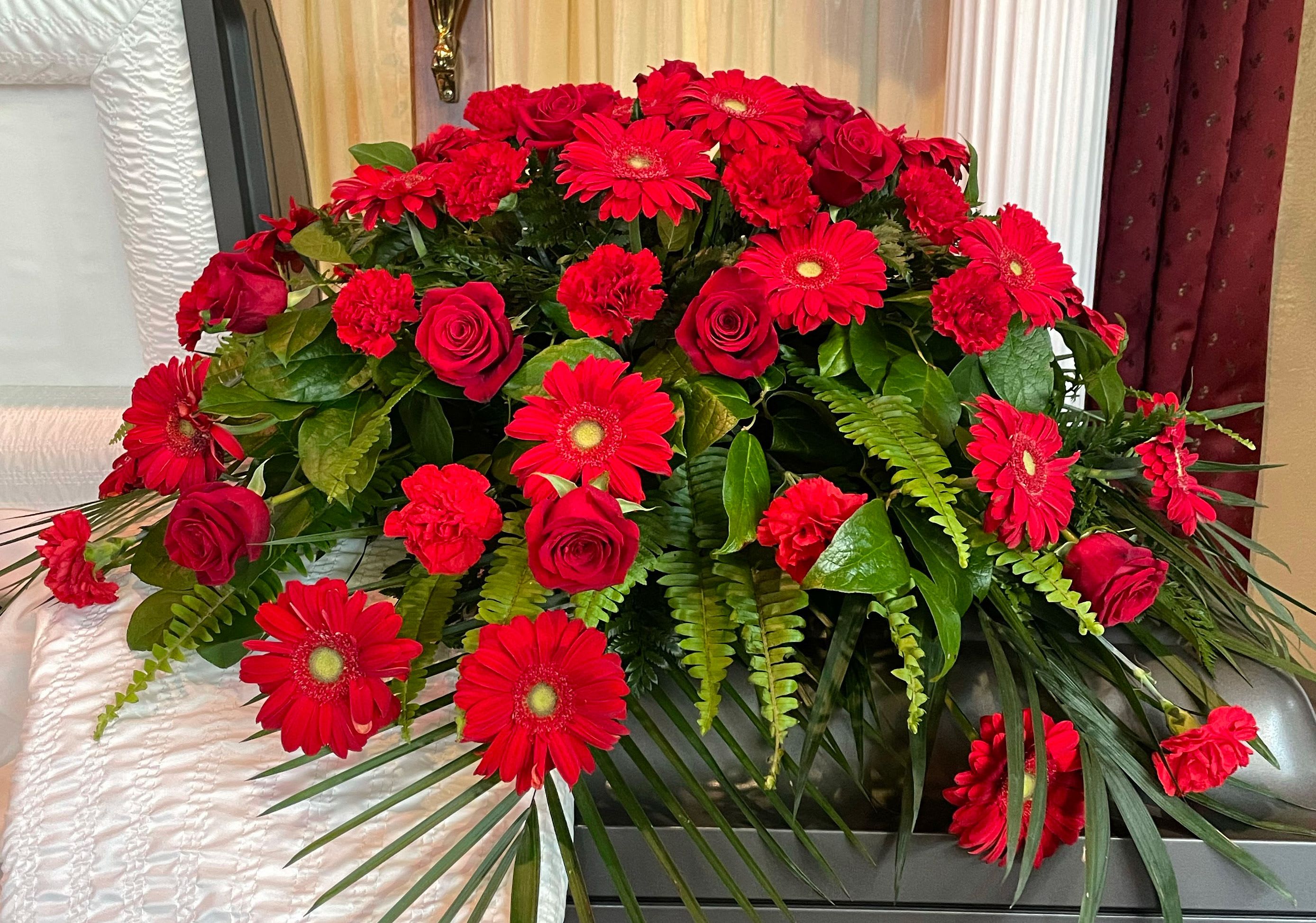 Red roses and gerbera daisies arranged in a casket spray