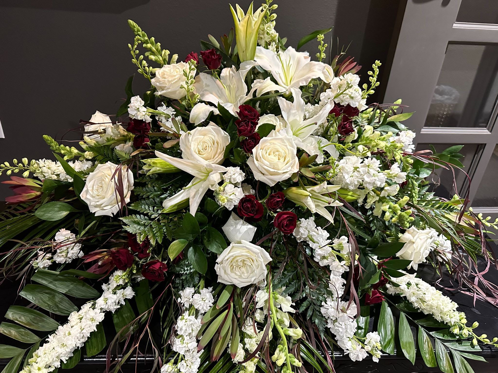 Large white and burgundy floral spray with lilies and roses