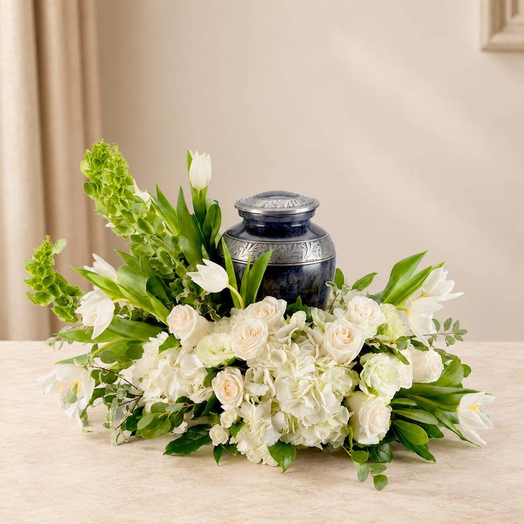 White floral arrangement with roses and tulips around a dark blue urn