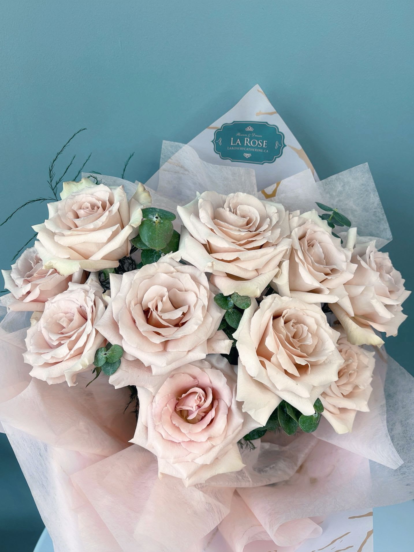 Bouquet of pale blush roses wrapped in pink paper