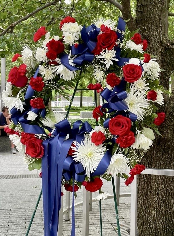 Large wreath of red and white flowers with blue ribbons on an easel