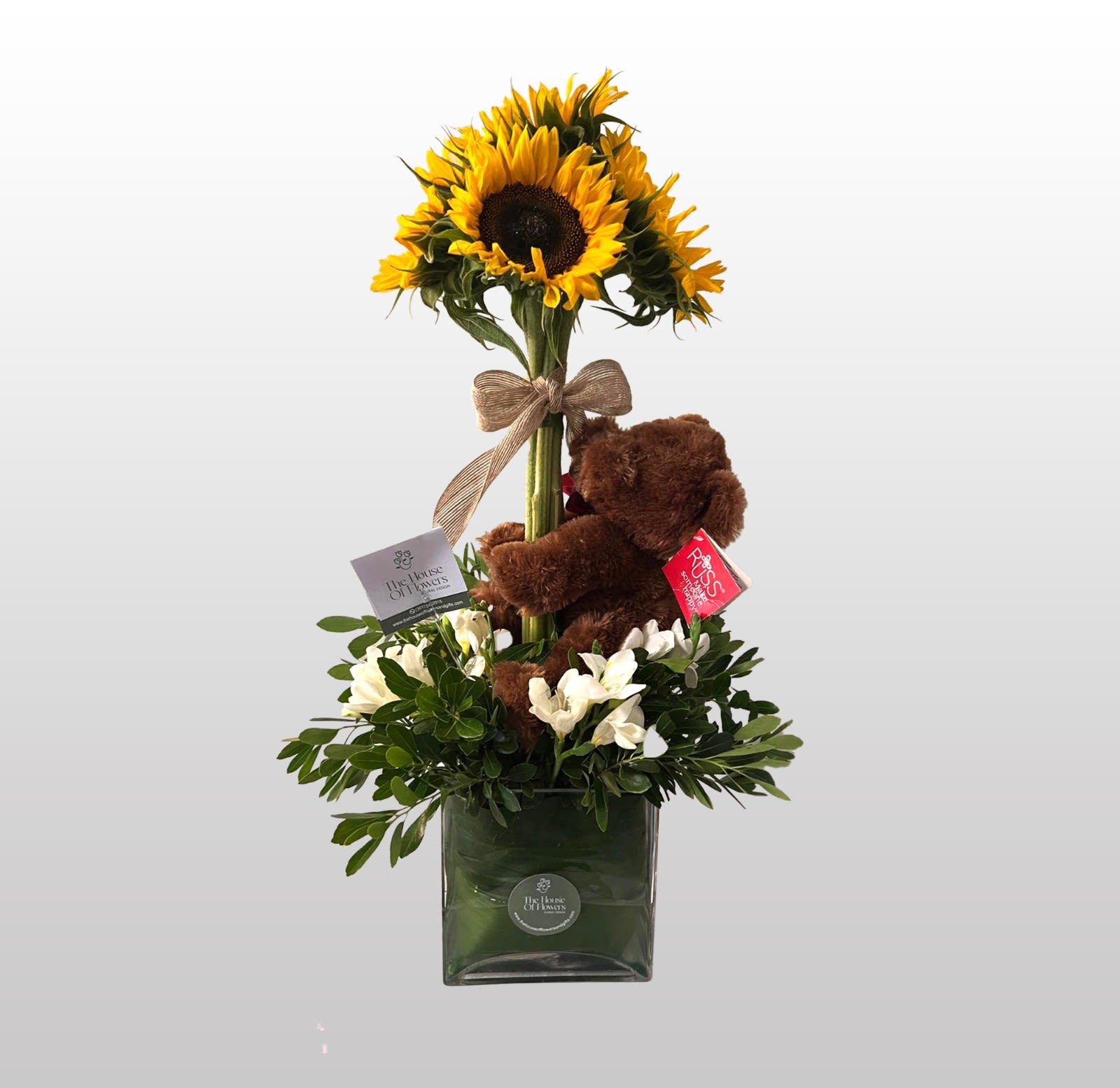 Welcome with Sunflowers by The House of Flowers - Let the sunflowers make the newborn's room brighter. the arrangement is accompanied by a teddy bear, to highlight the tenderness of the occasion.   APPROXIMATE DIMENSIONS OF THE BASE: 5" H, 5"L 