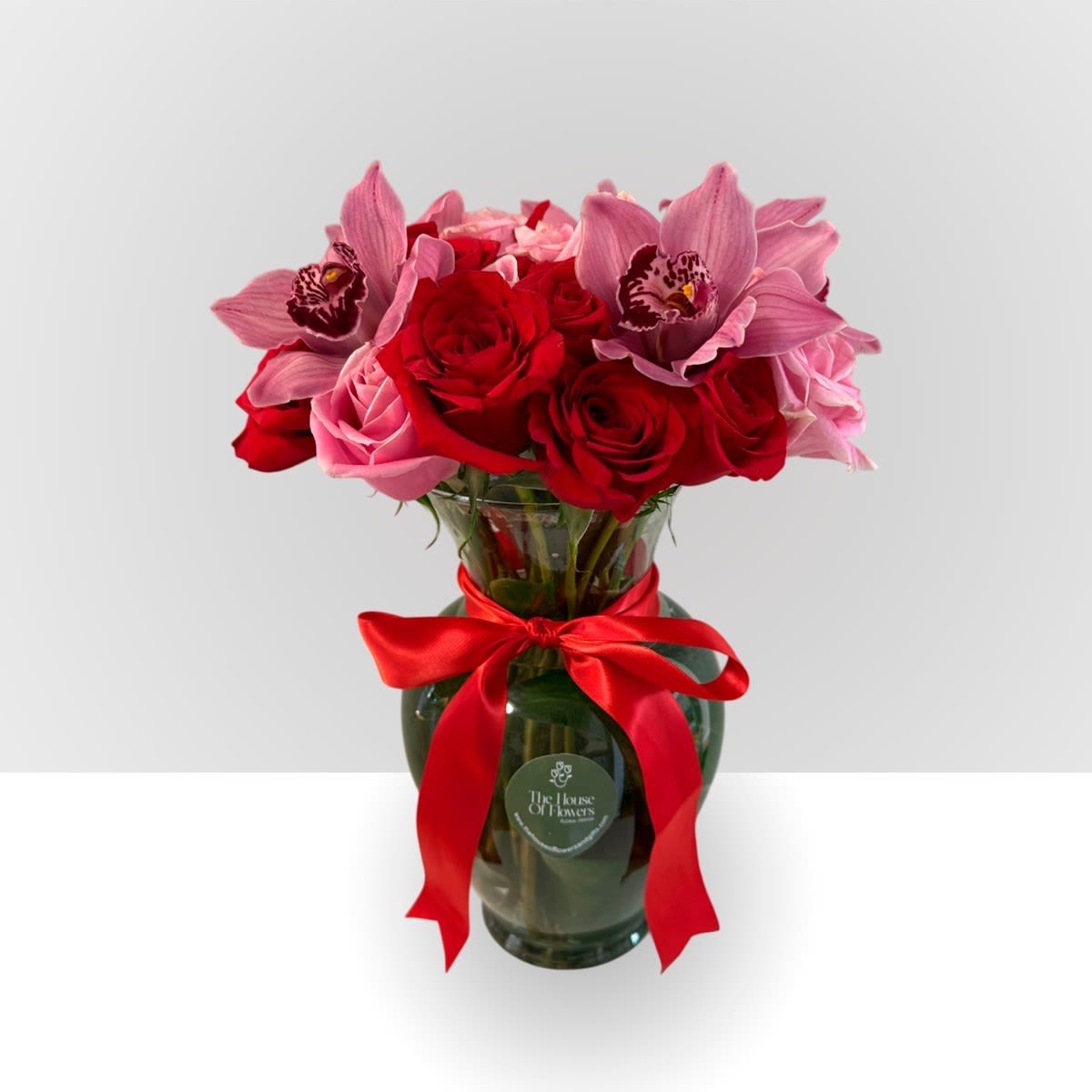Bouquet of red and pink roses with pink orchids in a glass vase