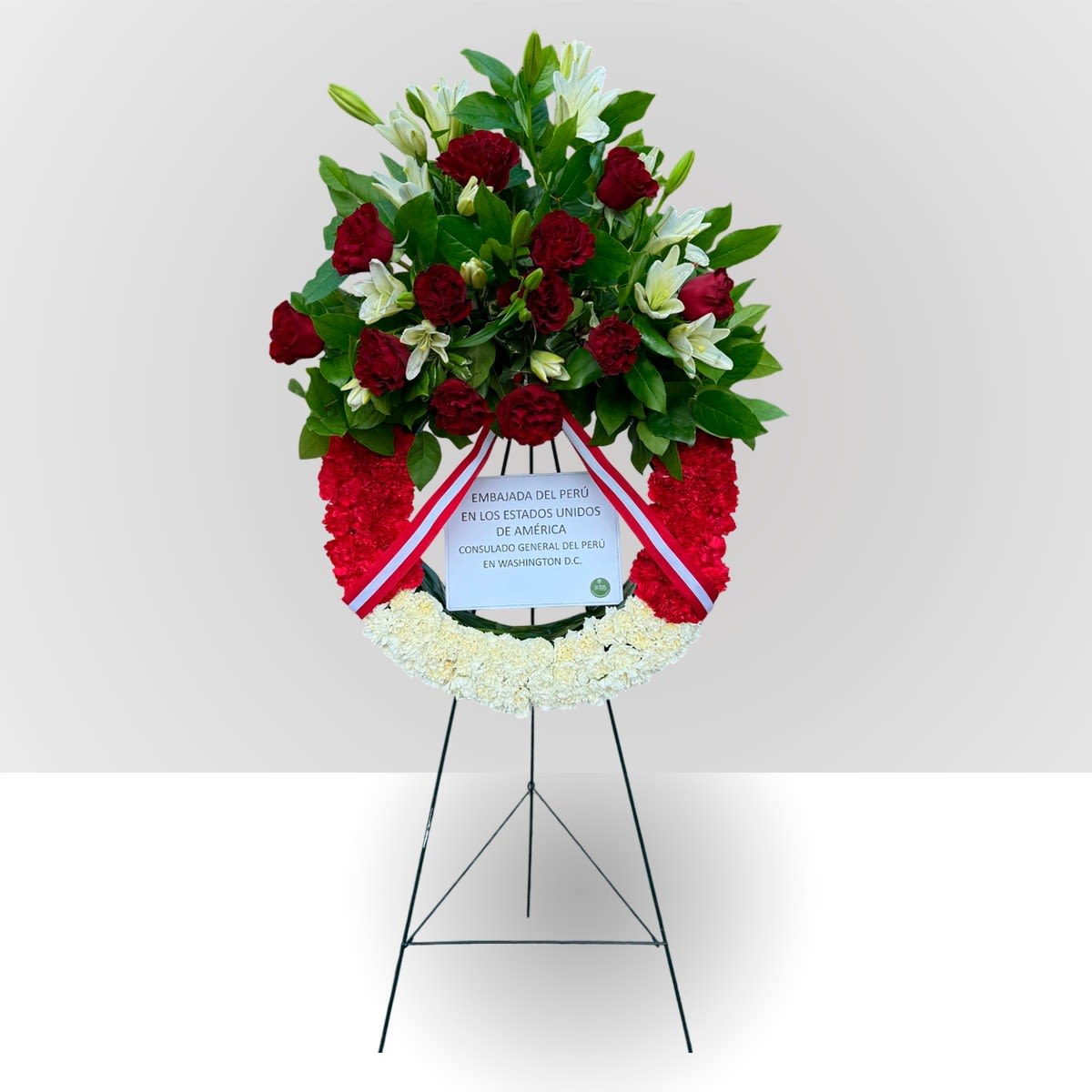Standing floral wreath with red and white flowers on an easel