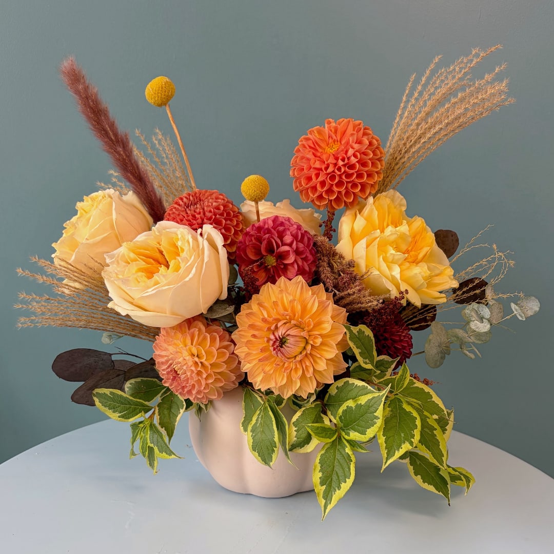 Orange and yellow floral arrangement in a white vase
