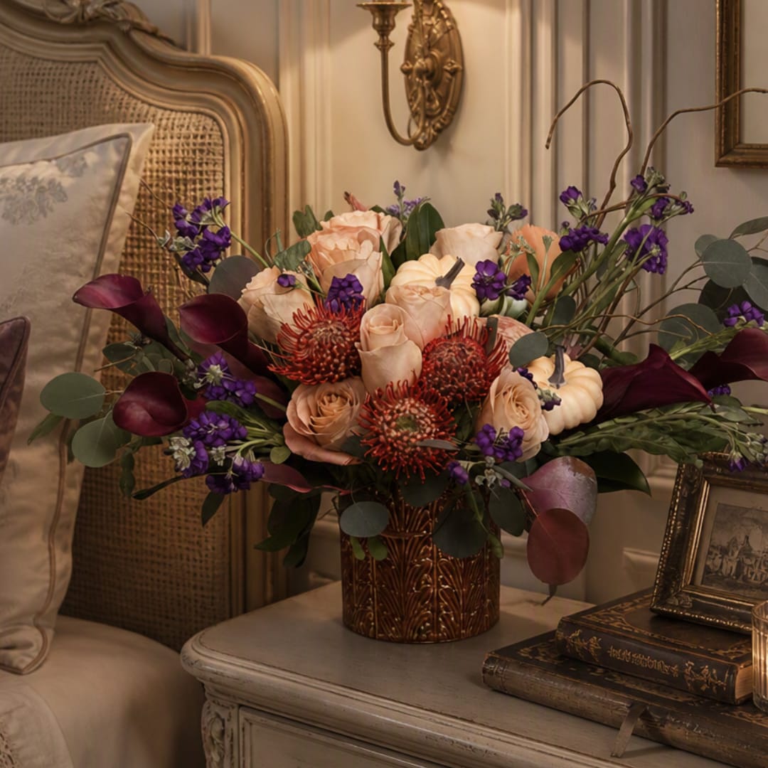Peach roses and purple flowers arranged in a decorative vase