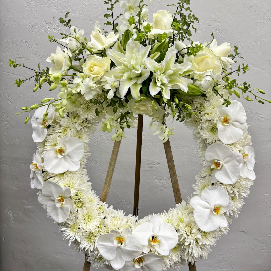 White floral heart wreath on a stand with orchids and lilies