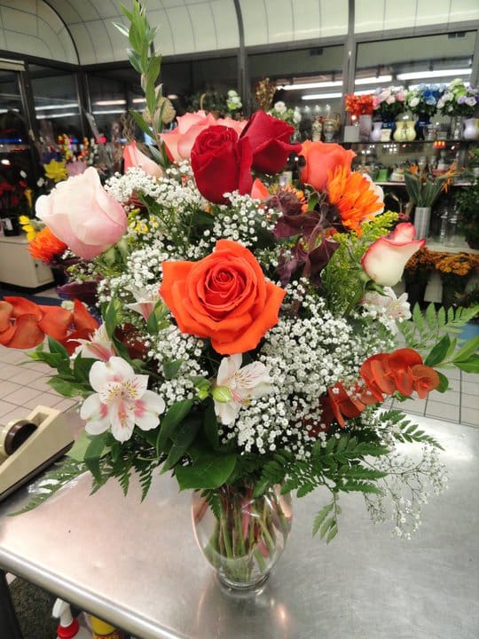 Mixed bouquet of roses and white filler flowers in a clear glass vase