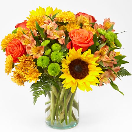 Bouquet of sunflowers, orange roses, and yellow mums in a glass vase