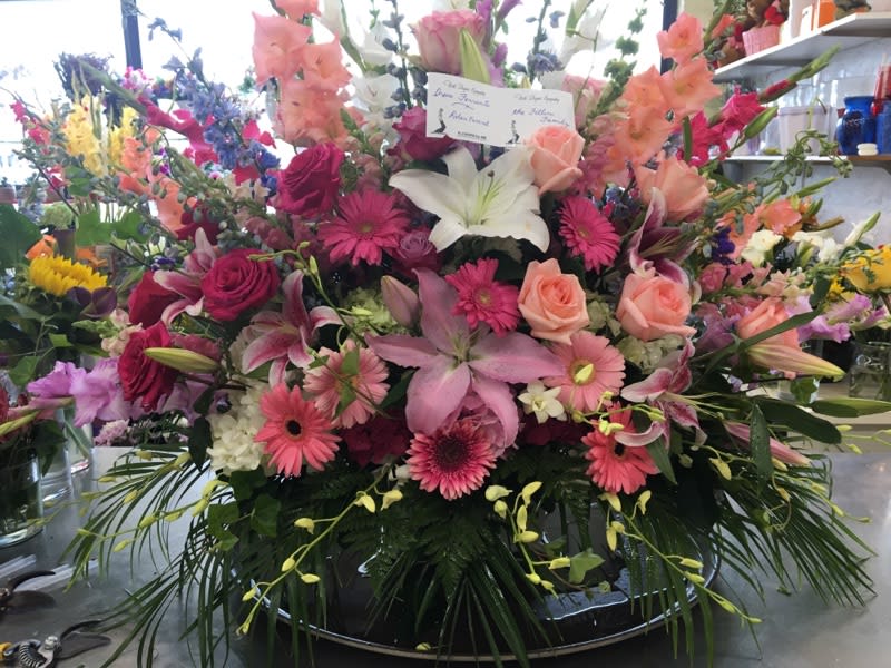 Large mixed flower arrangement with lilies, roses, and gerbera daisies in a low container