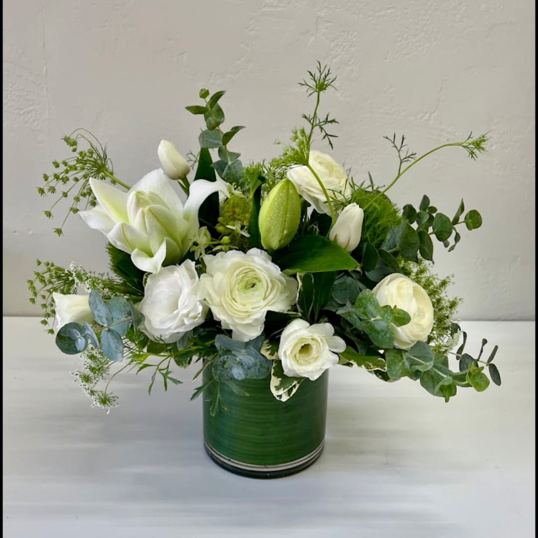 White flowers arranged in a green vase with airy greenery
