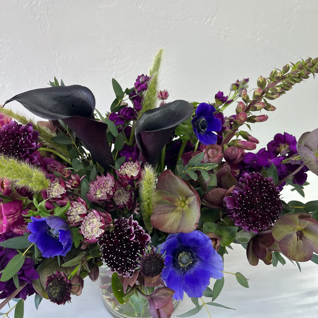 Purple and blue floral arrangement in a clear glass vase