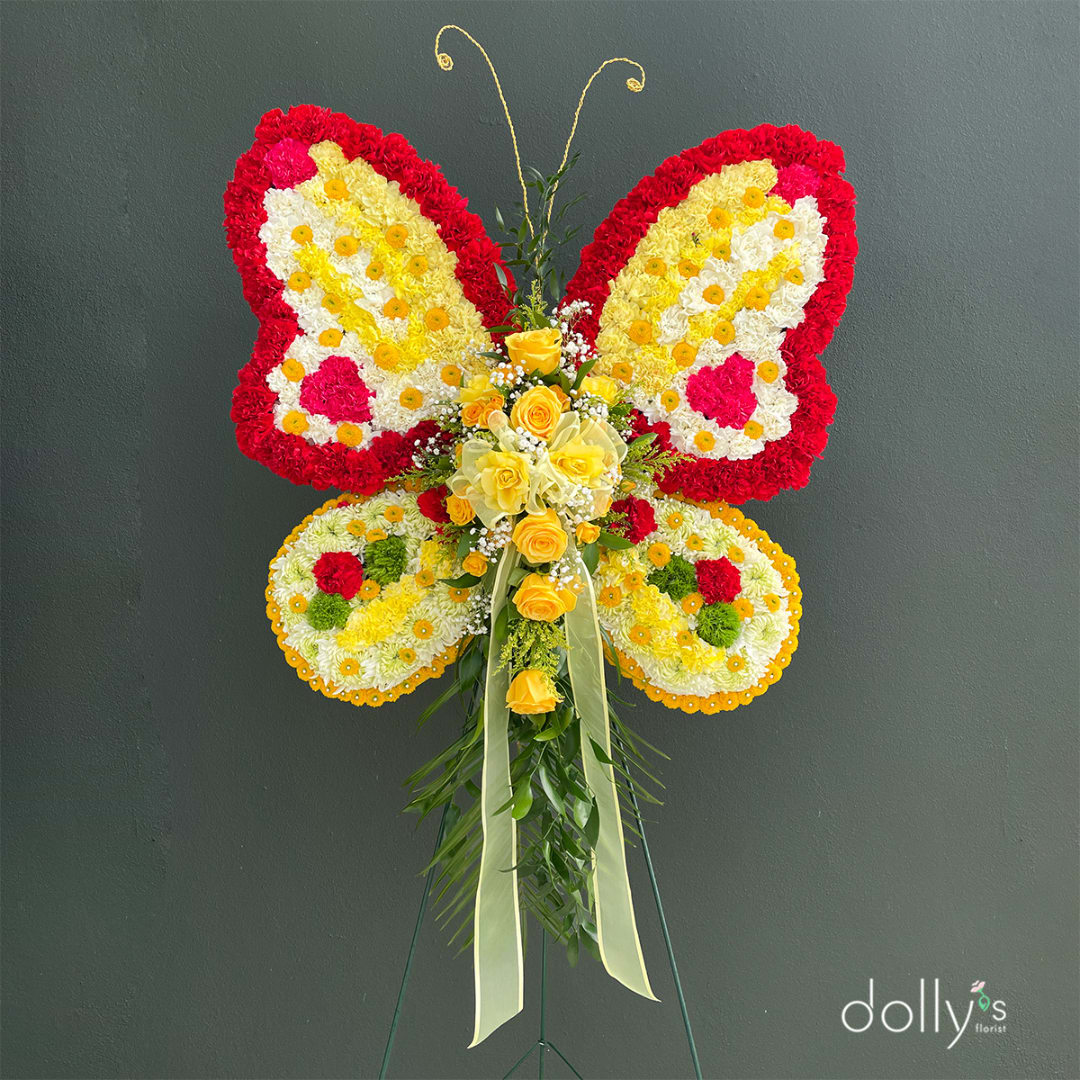 Butterfly-shaped floral standing arrangement with yellow roses and red, white, and yellow flowers