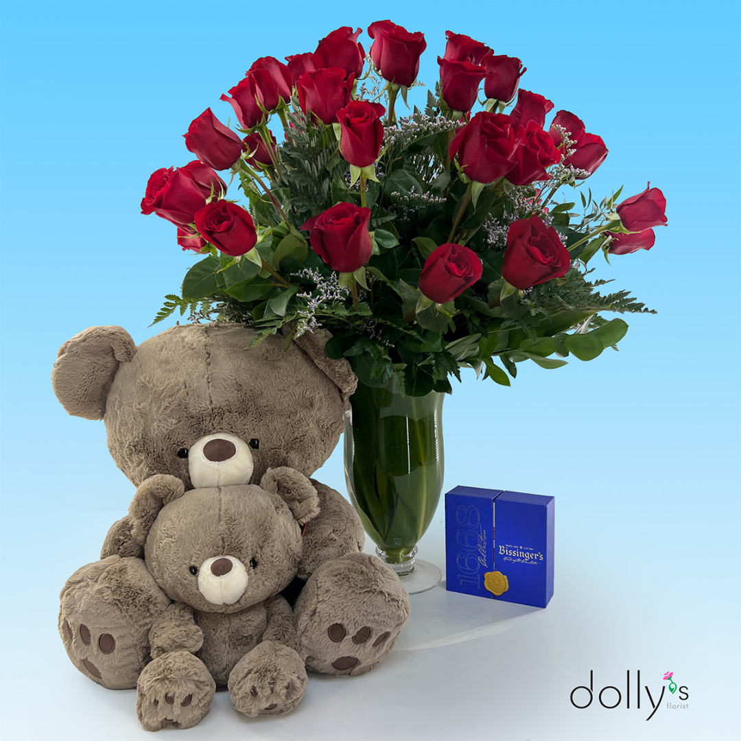 Red roses in a glass vase with two teddy bears and a chocolate box