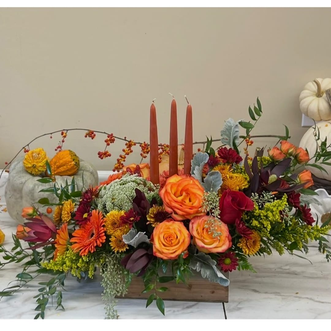 Autumn floral centerpiece with orange roses and red candles