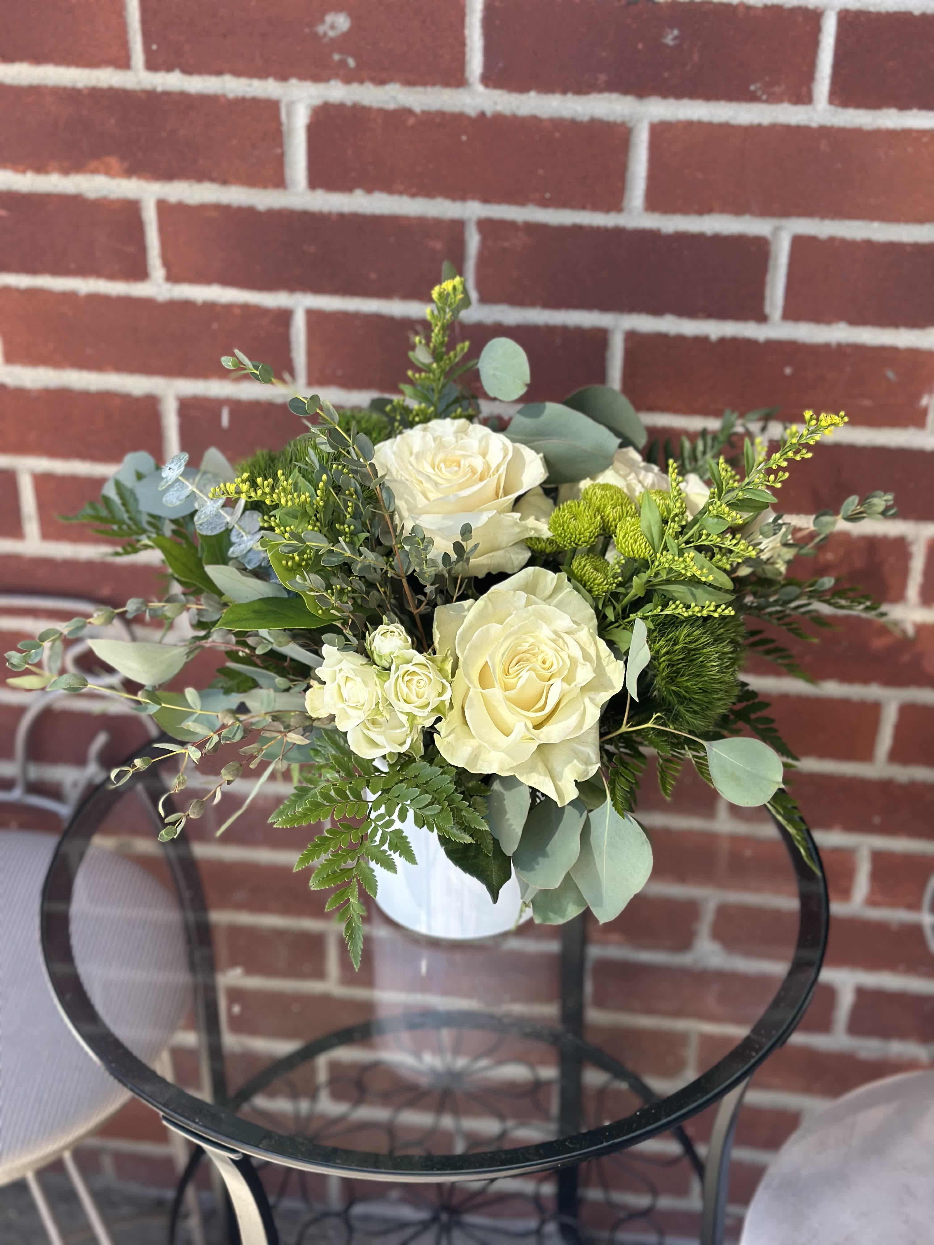 White rose bouquet in a white vase with mixed greenery