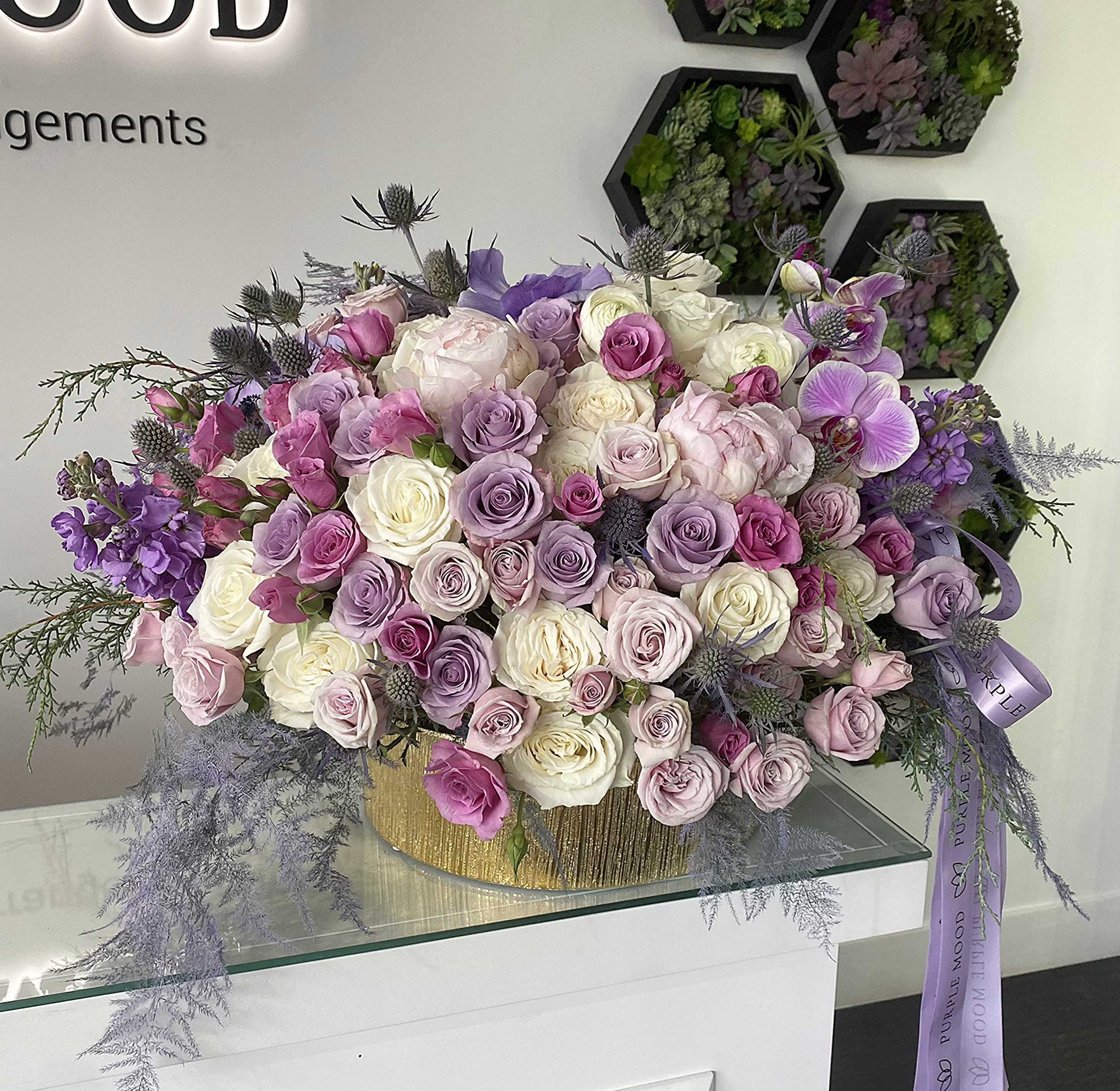 Dreamland Vase - Round gold vase, large. Step into elegance with the Dreamland Vase — a grand, luxurious arrangement overflowing with premium roses in a romantic palette of lavender, lilac, blush pink, and creamy white. Accented with soft fillers and airy greenery, this arrangement feels both enchanting and sophisticated. Presented in a stylish gold vase, it’s designed to make an unforgettable statement.   •    Premium roses in lilac, lavender, blush, pink, and cream     •    Elegant fillers and soft greenery for a dreamy texture     •    Presented in a gold vase for a luxurious finish     •    Perfect for weddings, anniversaries, or luxury gifts