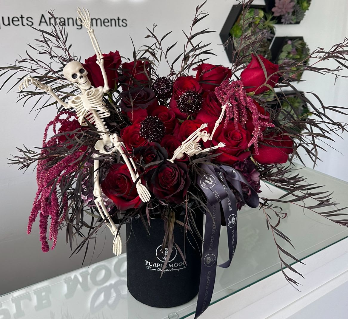 Red roses in a black box with small skeleton decorations