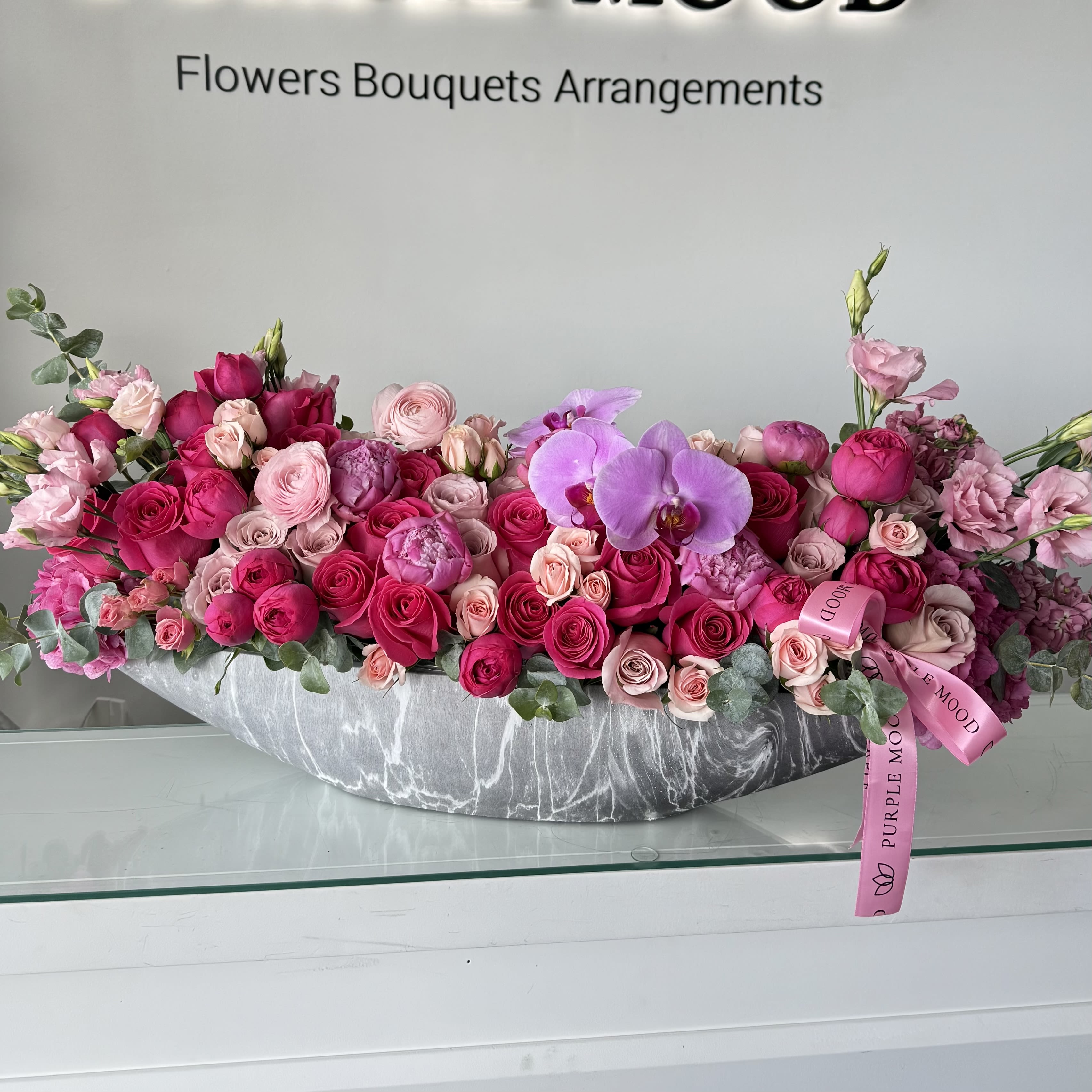 Long pink and purple flower arrangement in a gray vase