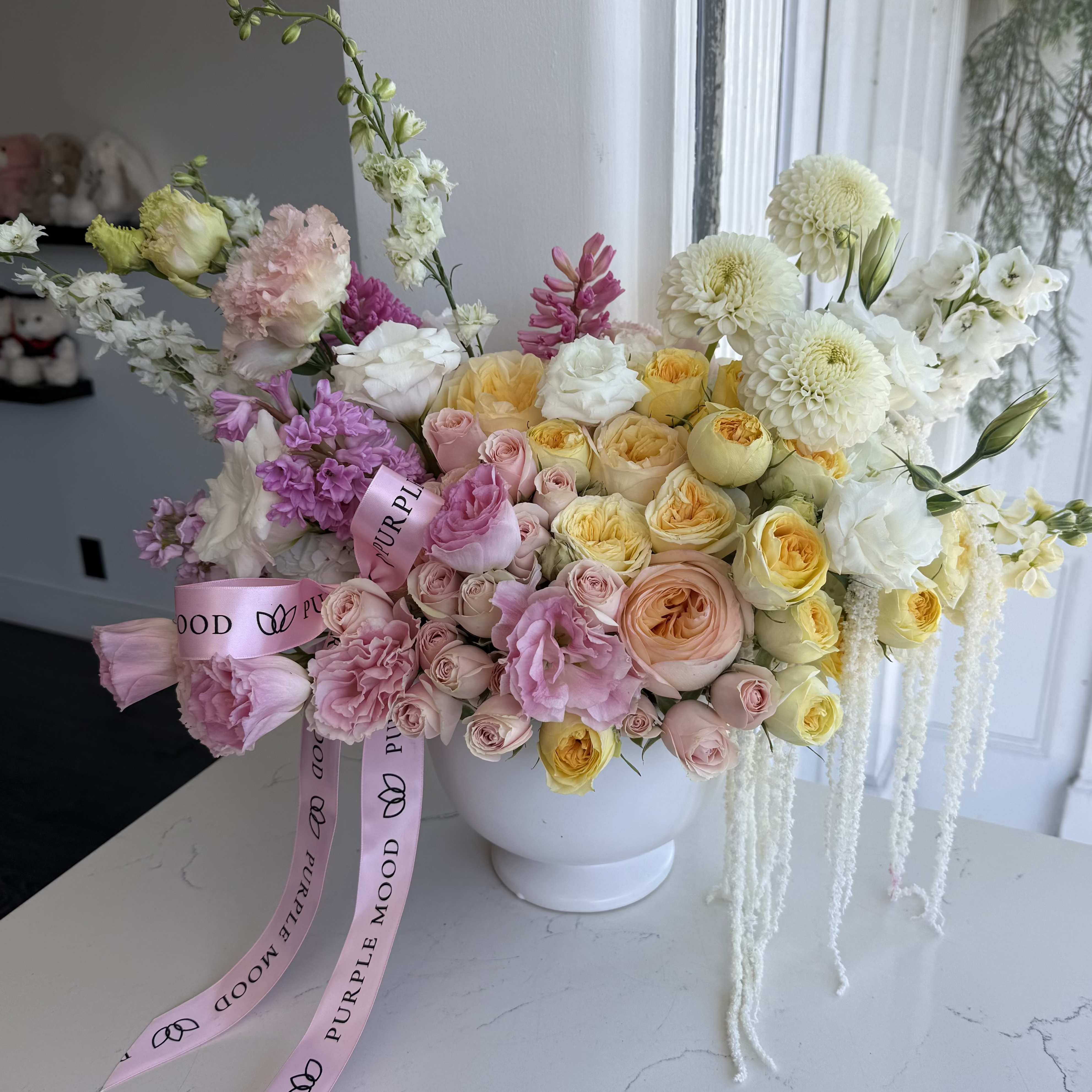 Creamy Lemon Vase - A delicate floral arrangement in a ceramic vase, filled with soft cream, blush pink, and sunny yellow tones that bring warmth and light into any space. Lush roses, elegant ranunculus, and seasonal blooms create an airy, romantic feel, while flowing accents add a graceful, modern touch. Finished with a soft ribbon for an extra hint of charm. A perfect gift that speaks of love, care, and effortless beauty