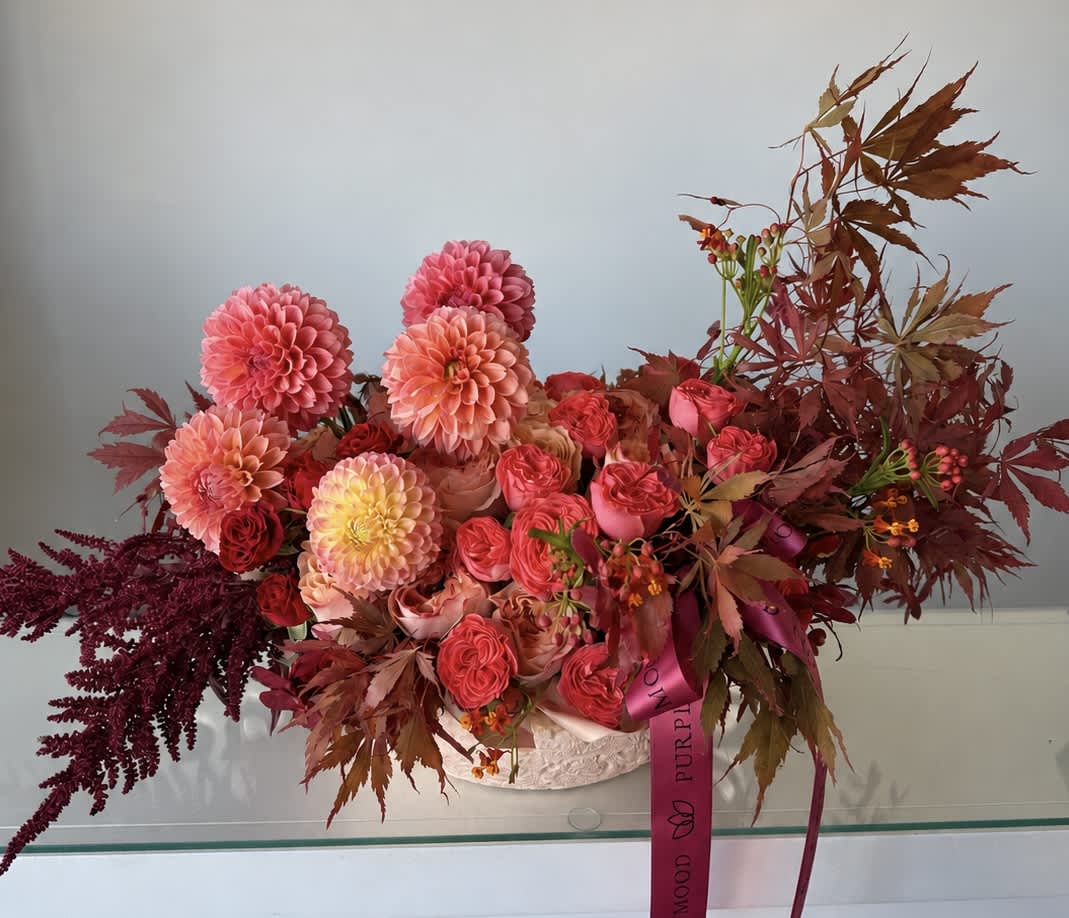 Pink and peach floral arrangement with roses and dahlias in a white container