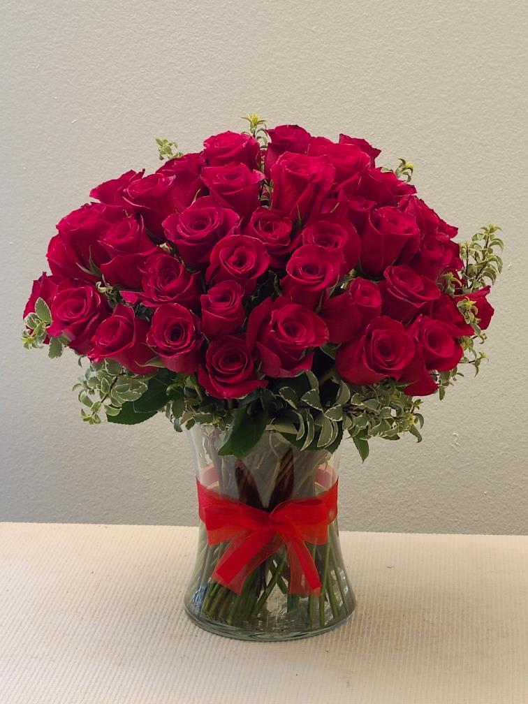Bouquet of red roses in a clear glass vase with a red ribbon