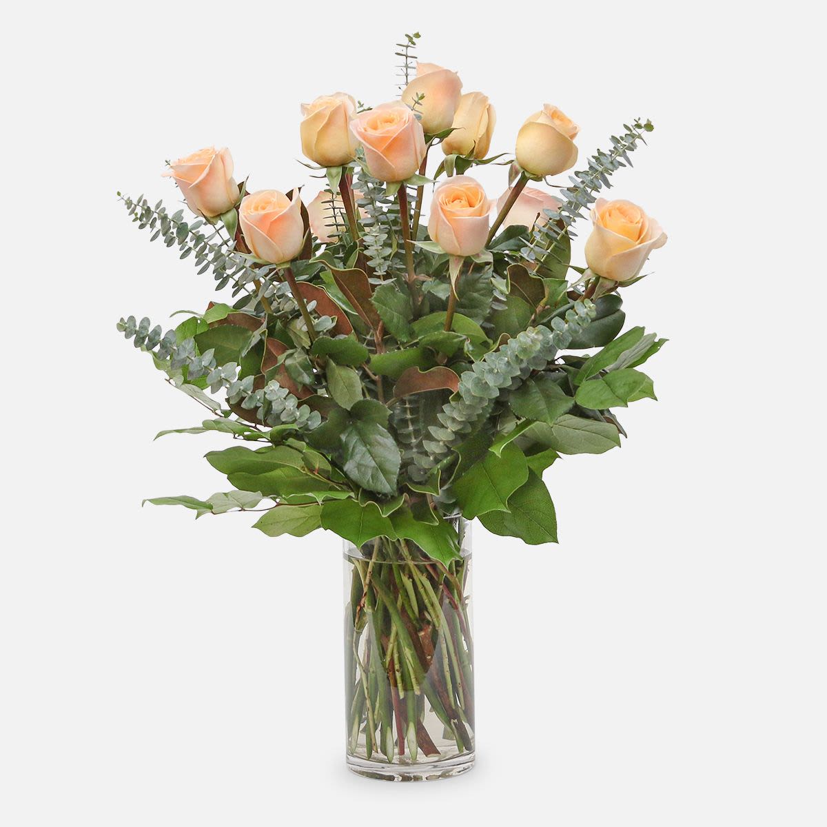 Peach roses in a clear glass vase with eucalyptus