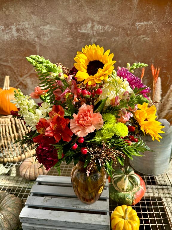 Mixed bouquet with sunflowers, carnations, and alstroemeria in a glass vase
