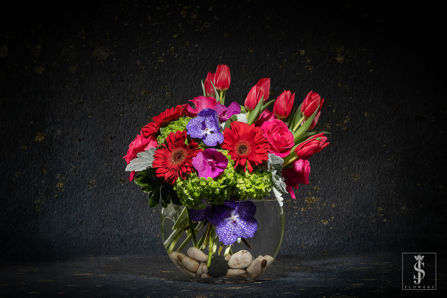 Bright mixed bouquet in a round glass vase with stones