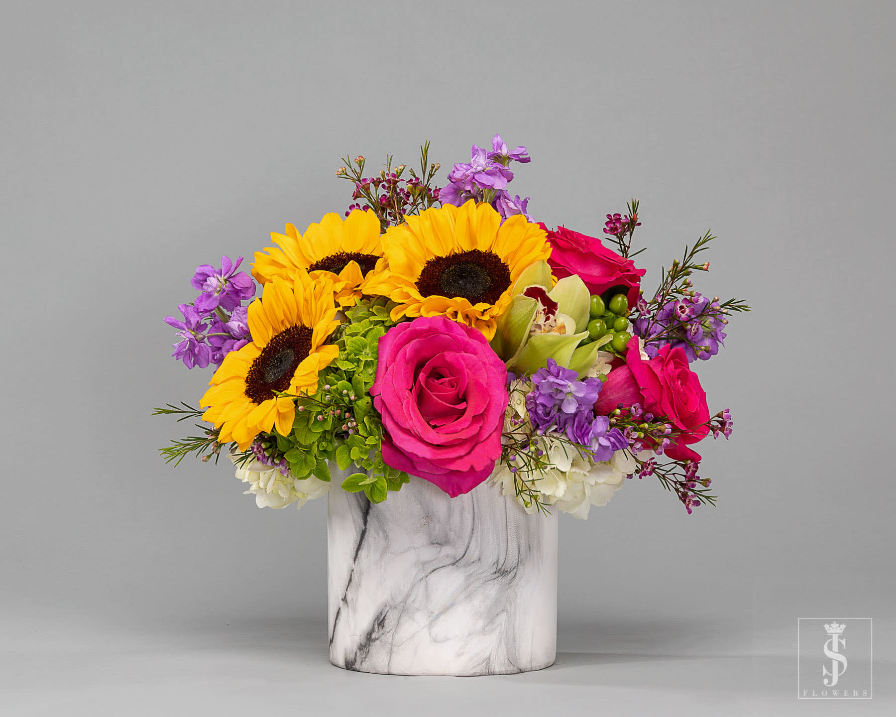 Bright mixed bouquet in a marble-pattern vase with sunflowers and pink roses