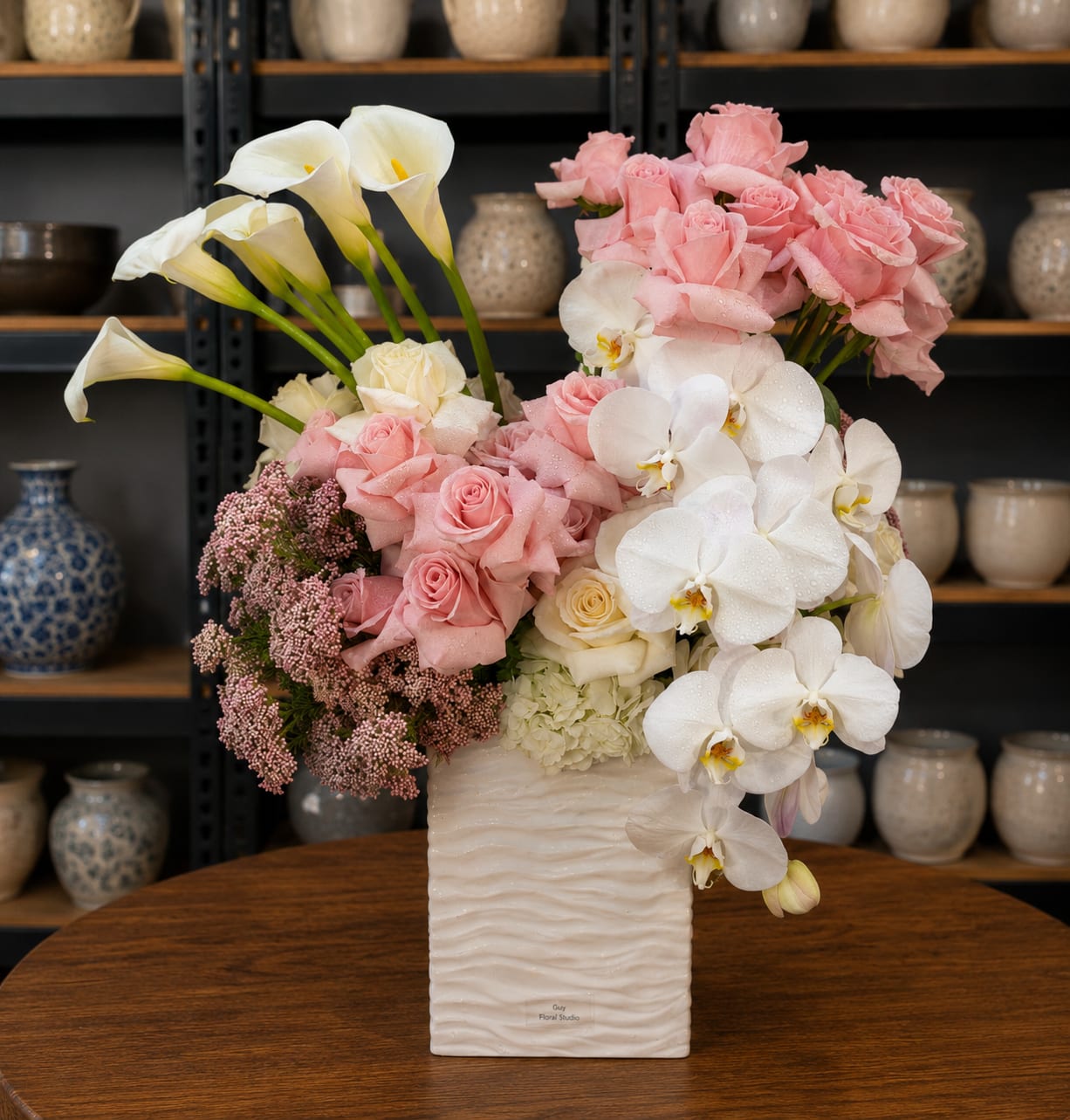 Pink roses and white orchids in a white vase with calla lilies