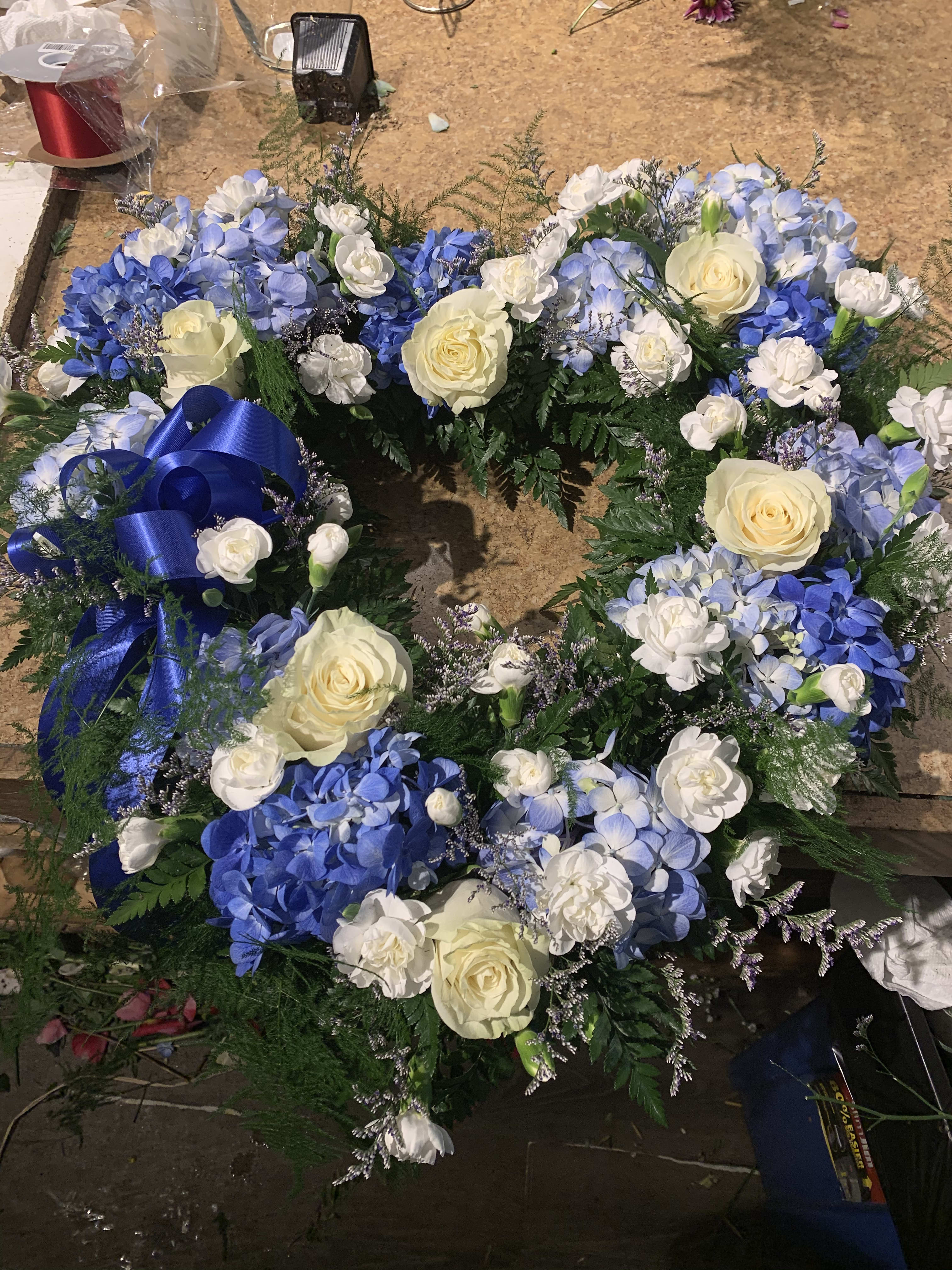 Blue and white floral wreath with cream roses and a blue ribbon